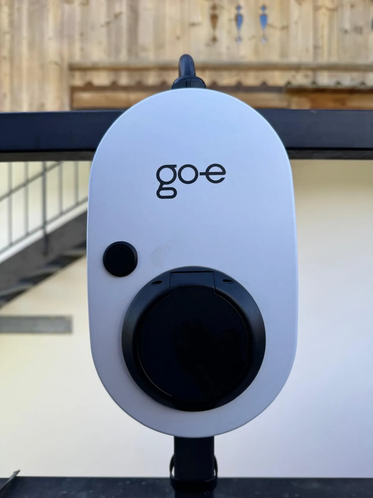 Shared amenity: An electric vehicle charging station is mounted beside a railing.