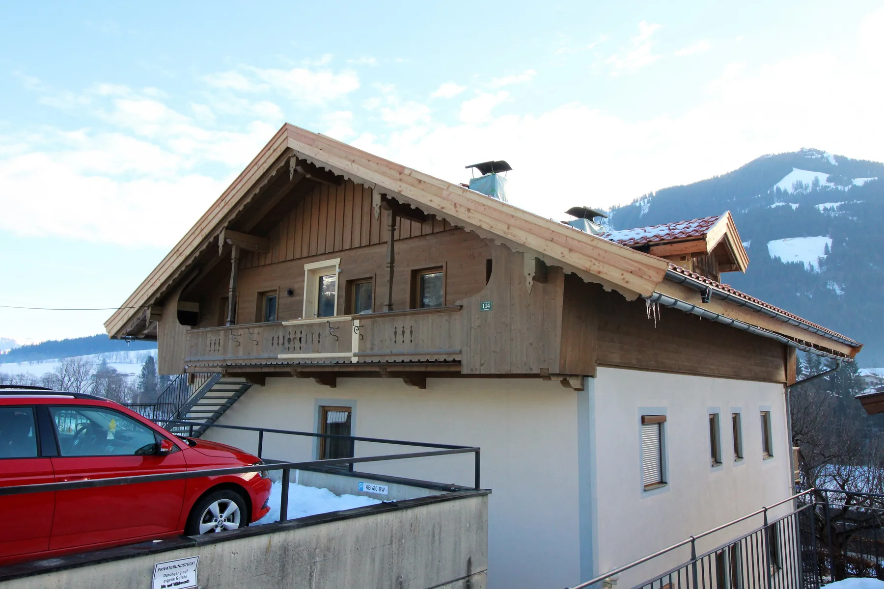 Shared amenity: A chalet-style building stands beside a parked car, with snowy mountains in the background.
