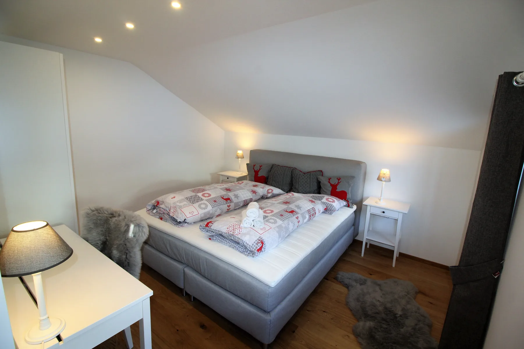 A bedroom with a double bed beneath a sloped ceiling and bedside tables.