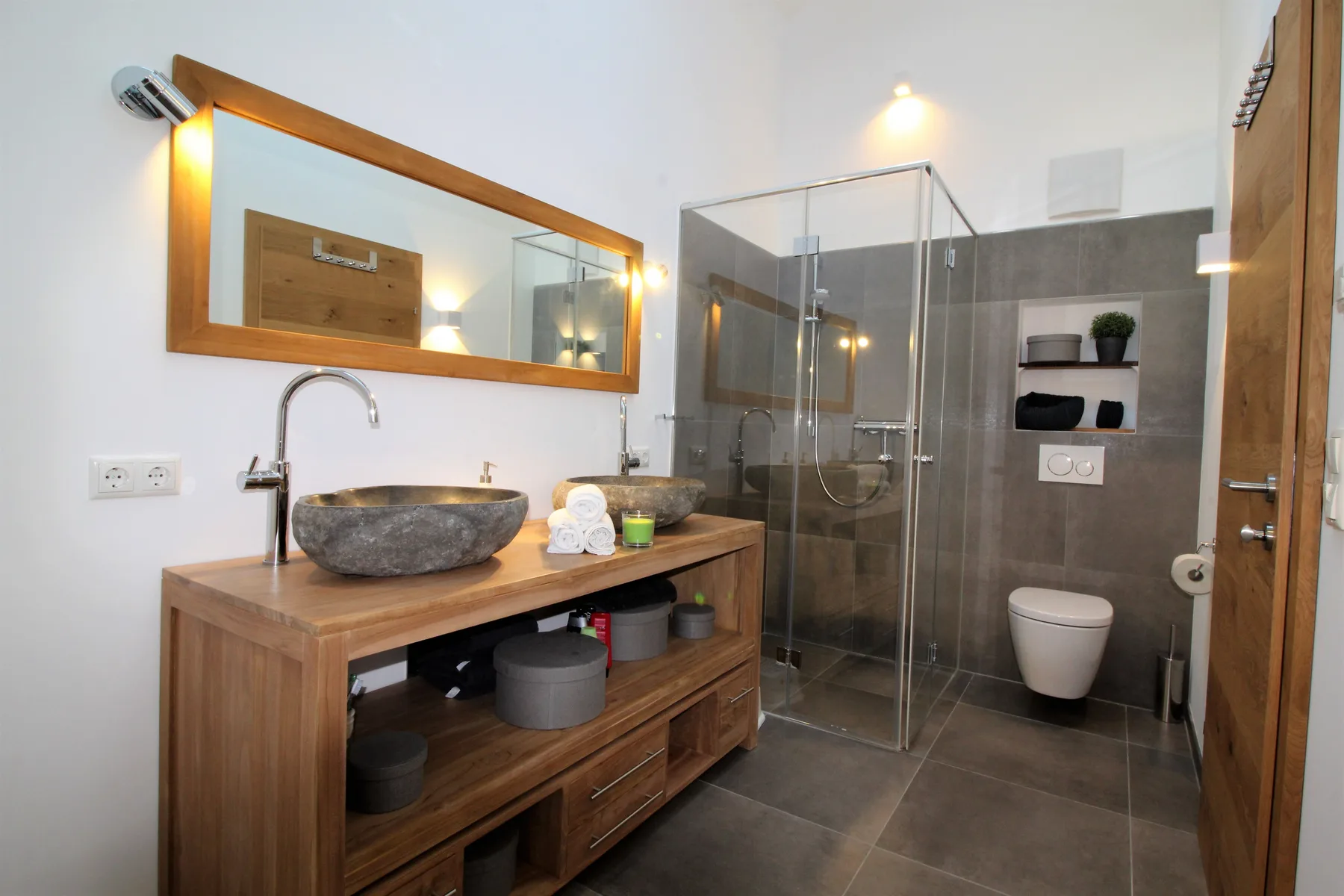 A bathroom with a wooden vanity, vessel sink, and glass shower.