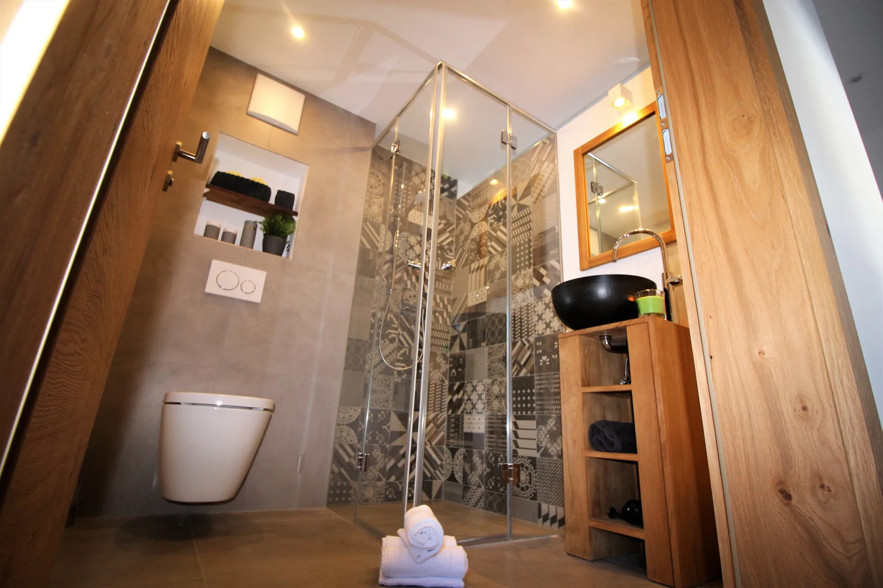 A modern bathroom with a glass shower and a wall-mounted sink.