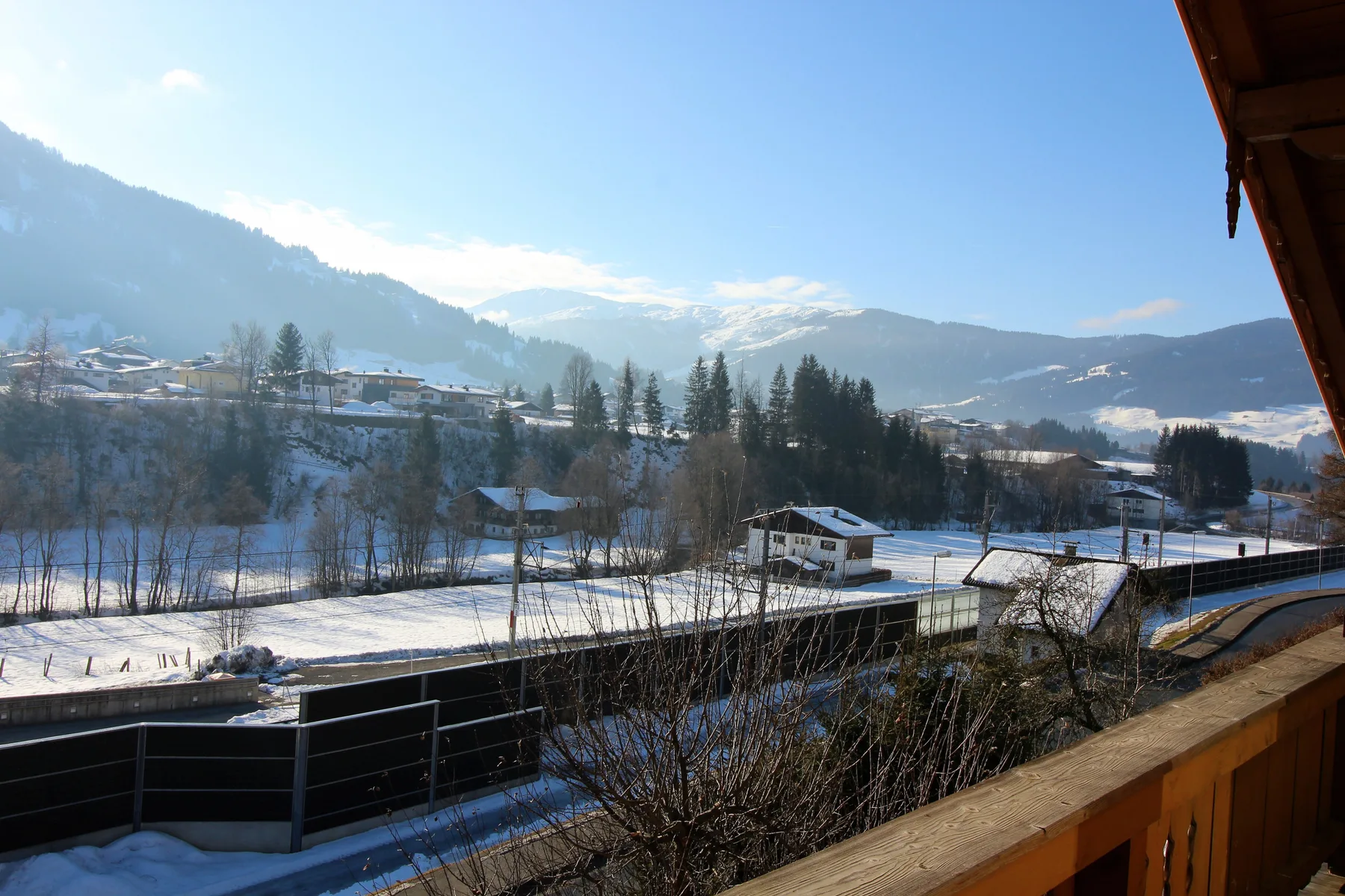 A snowy mountain valley with scattered buildings and trees beneath a clear sky.