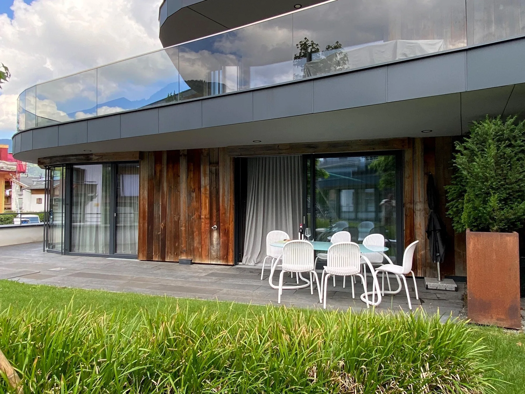 La fachada de un edificio moderno se abre a un patio exterior con asientos blancos.