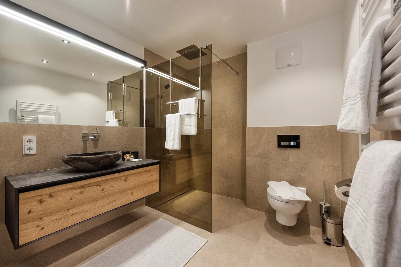 Un baño moderno con ducha de vidrio, lavabo suspendido e inodoro.
