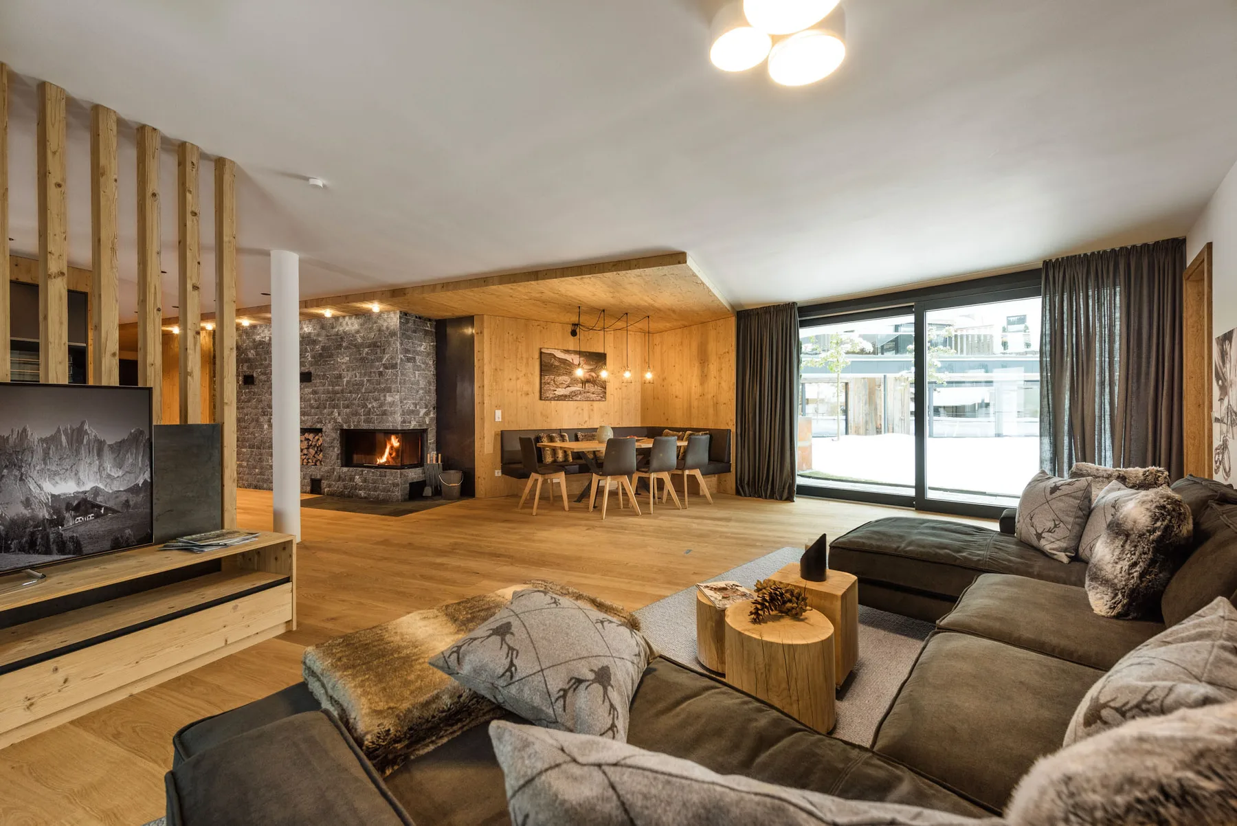 Una amplia sala de estar con comedor, chimenea y ventanales.