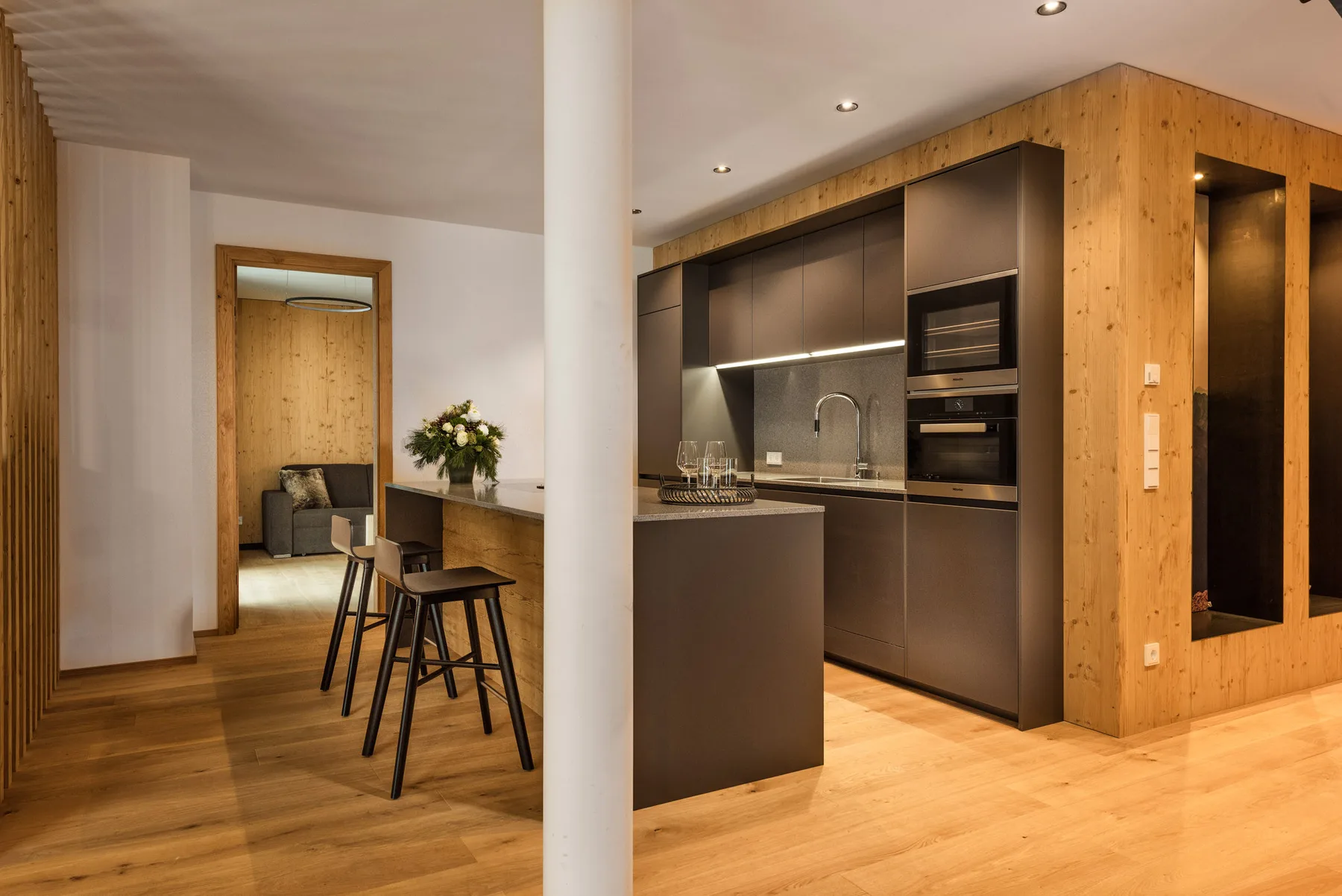 Una cocina moderna con una isla oscura y gabinetes de madera.