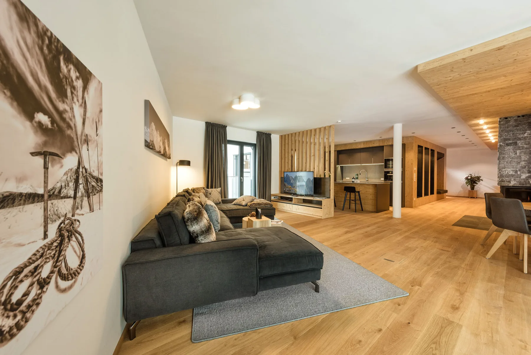 Una amplia sala de estar con zona de asientos, televisor y suelo de madera.