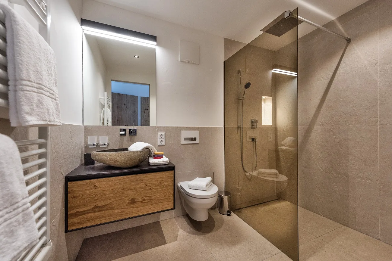 Un baño moderno con lavabo, inodoro y ducha con mampara de vidrio.