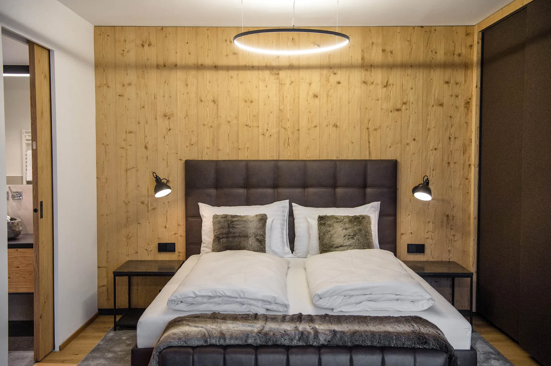 Un dormitorio con una cama doble frente a una pared revestida de madera.