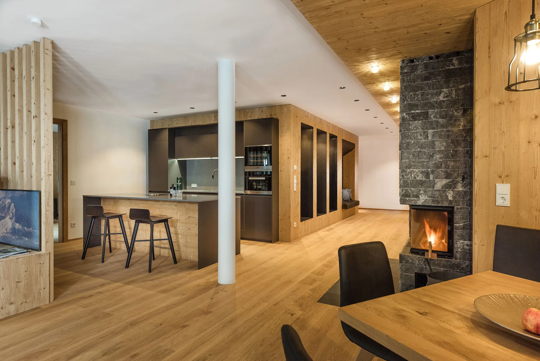 Una cocina y comedor de planta abierta con suelo de madera y una chimenea encendida.