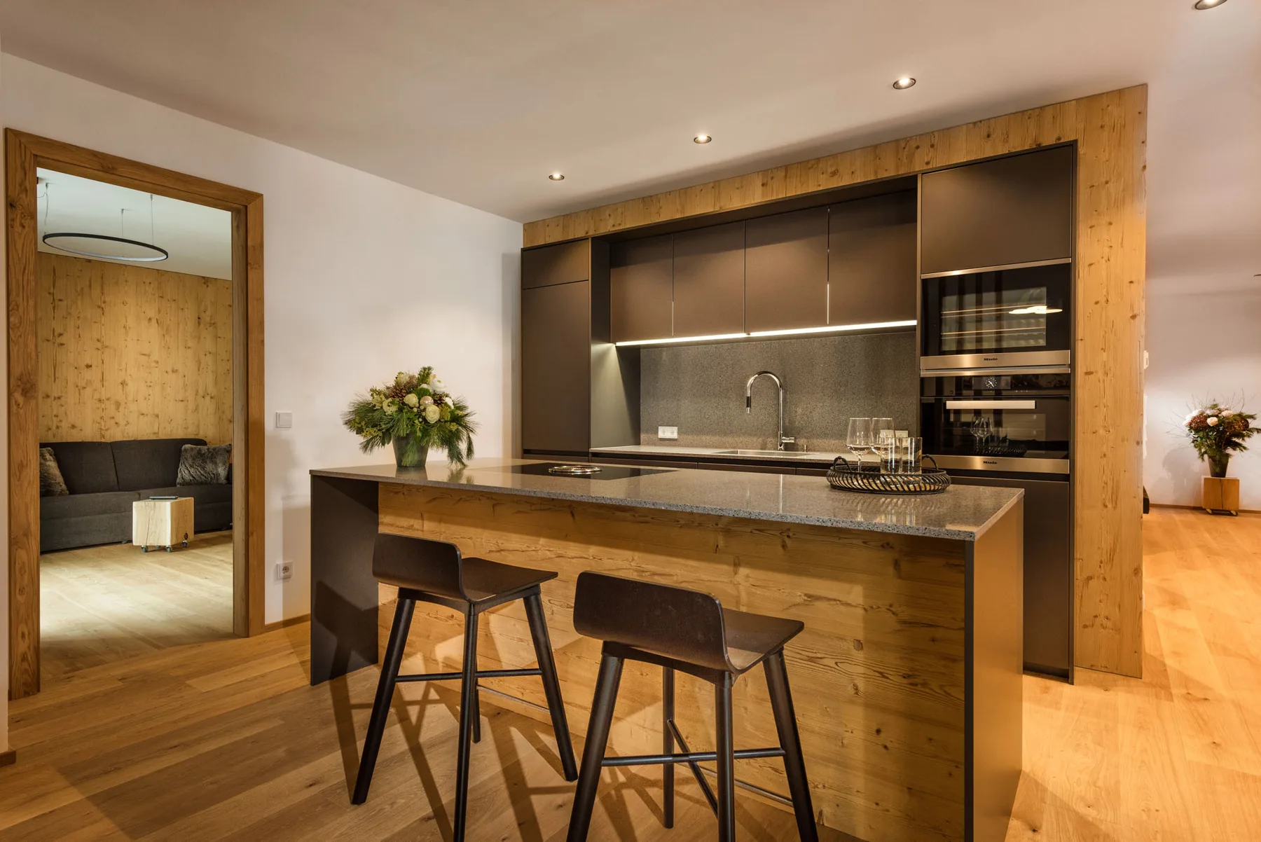 Una cocina moderna con una isla larga y gabinetes oscuros.
