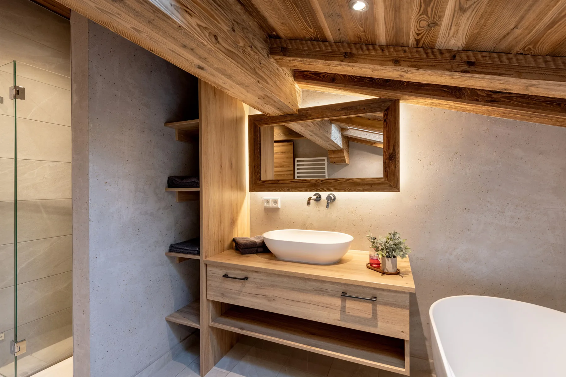 Un mueble de baño con lavabo y espejo bajo un techo revestido de madera.
