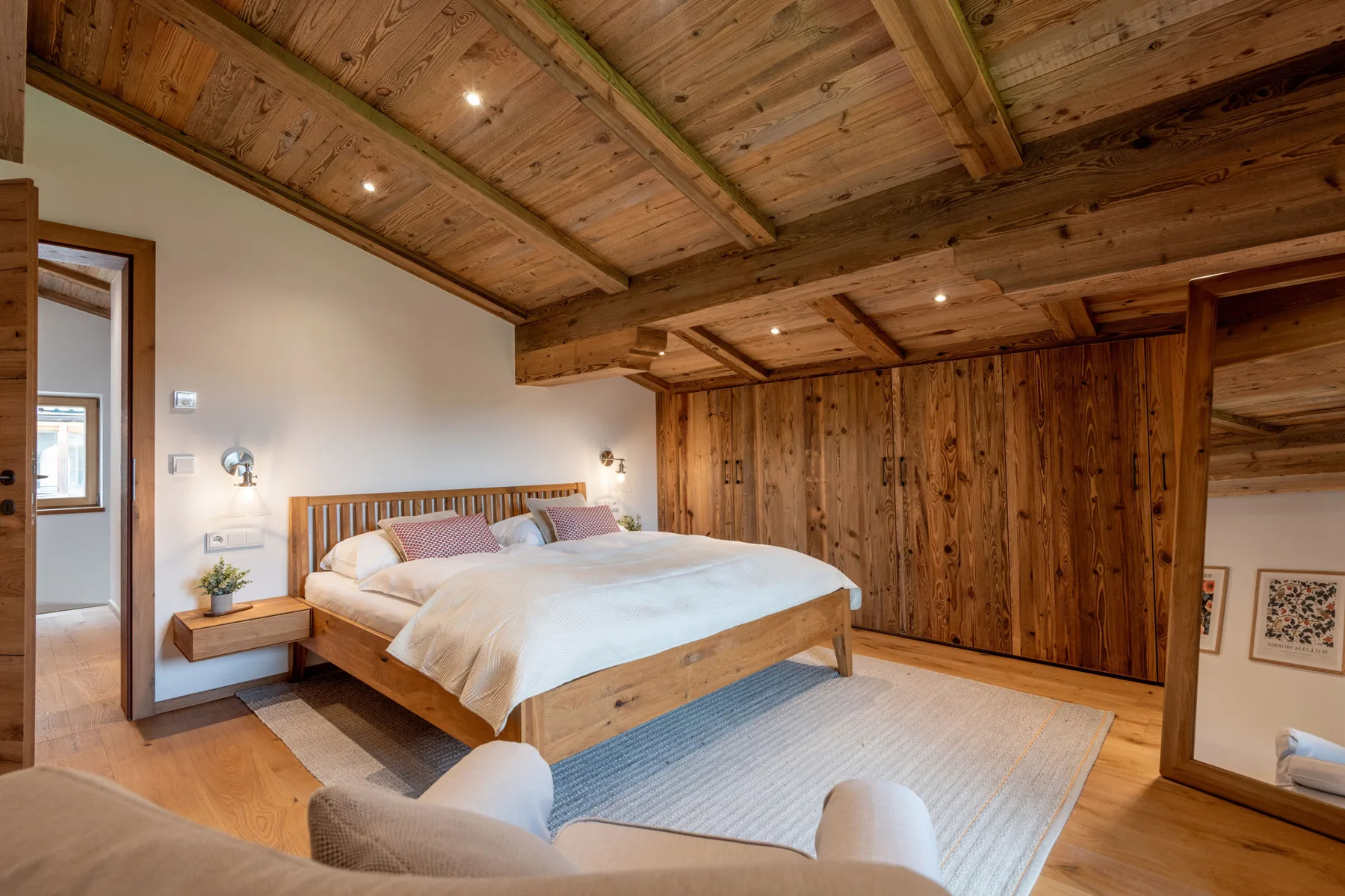 Un dormitorio con una cama de madera, ropa de cama blanca y techo inclinado de madera.