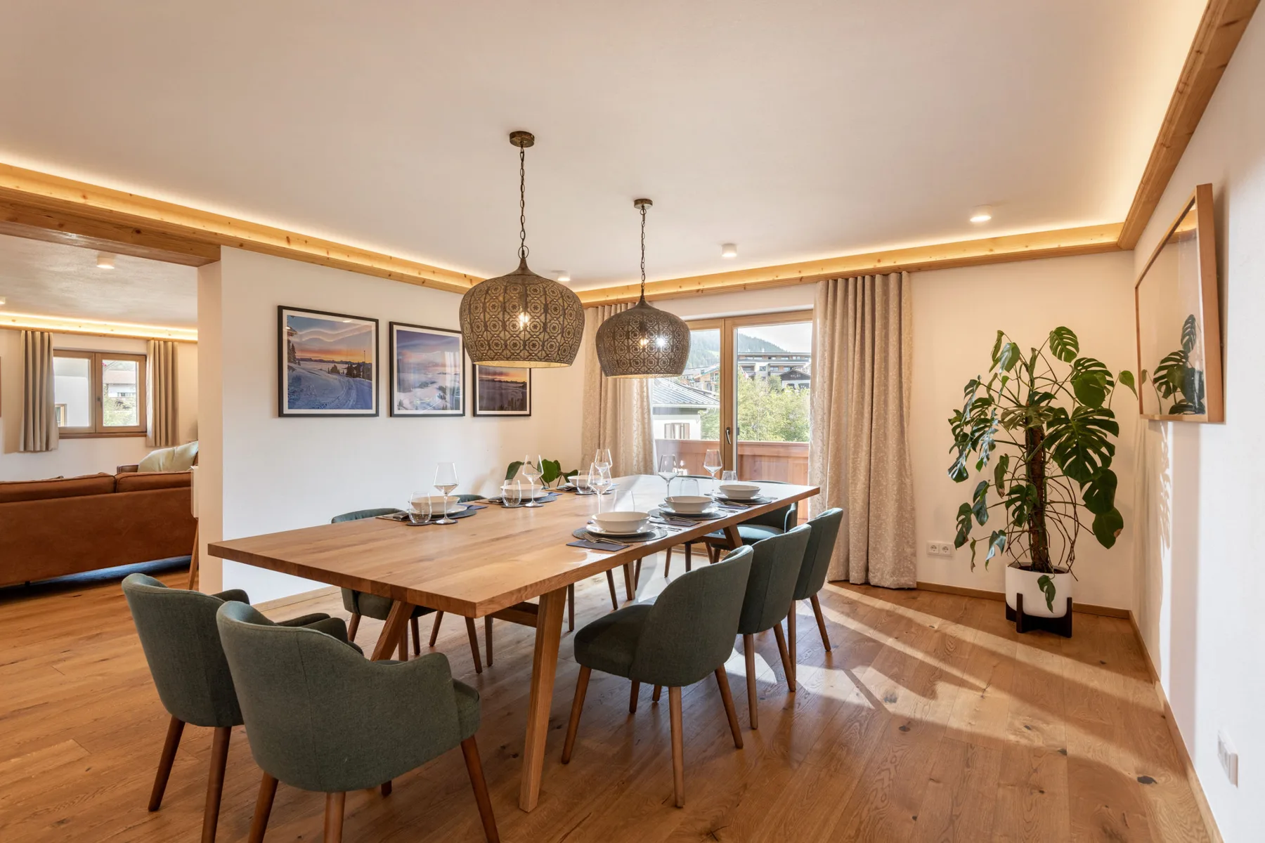 Comedor con una mesa de madera, asientos tapizados y lámparas colgantes.