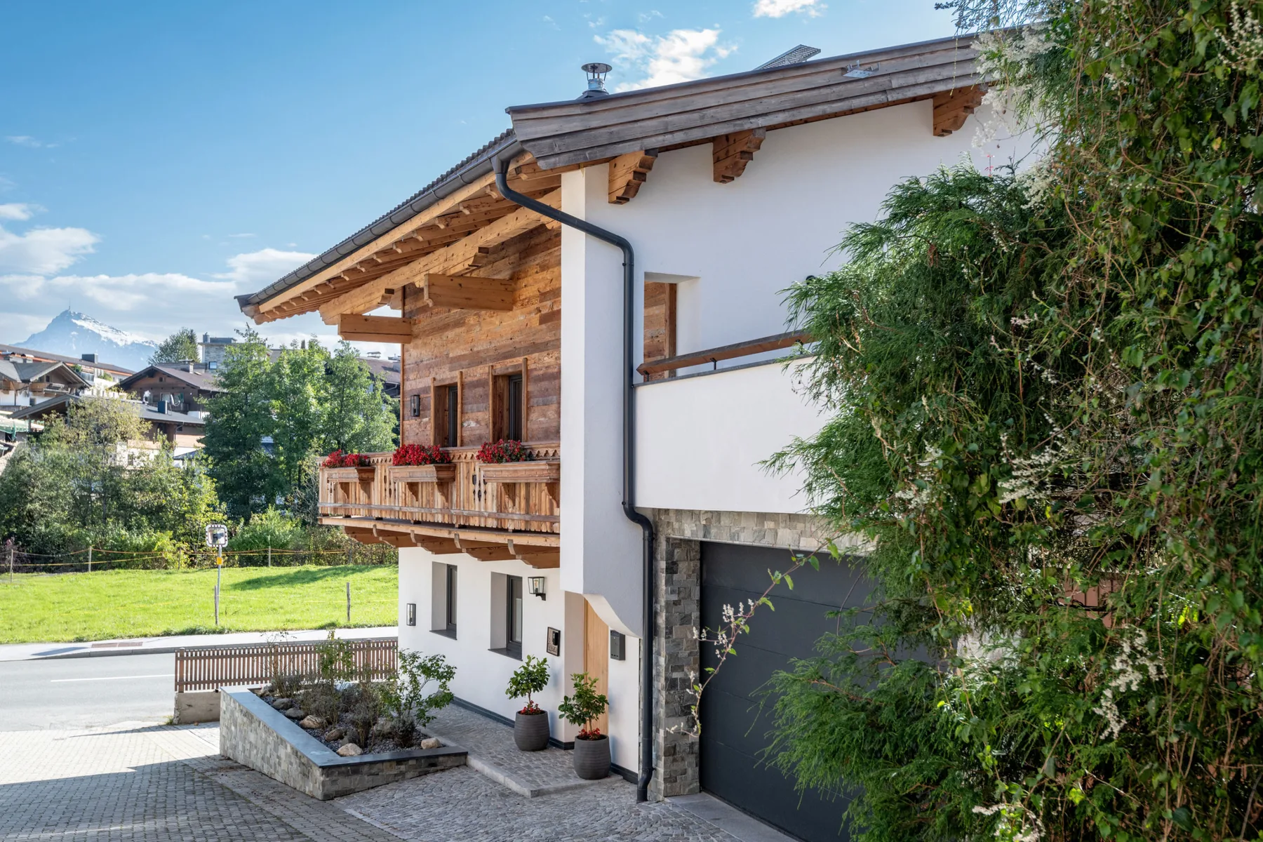 Un edificio de estilo chalet con balcones de madera junto a una entrada pavimentada.