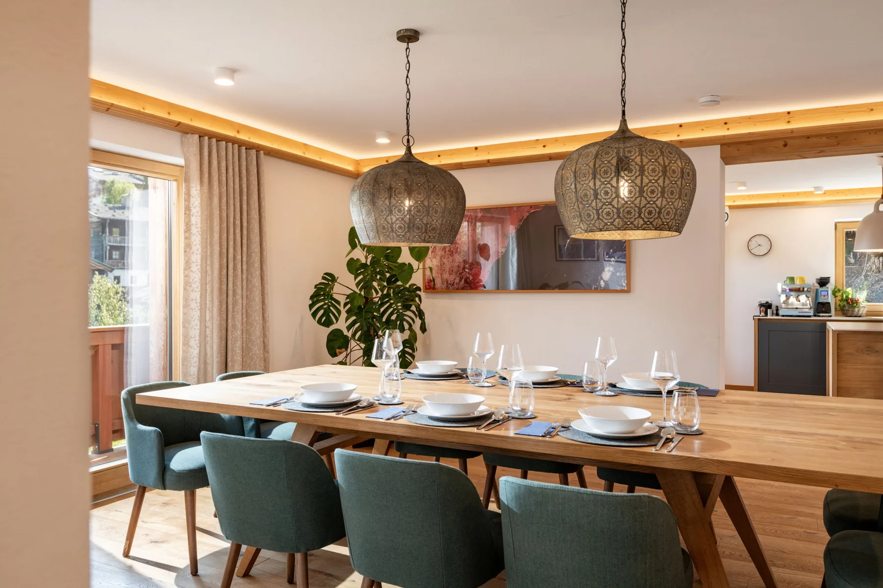 Comedor con una mesa larga, asientos tapizados y lámparas colgantes.
