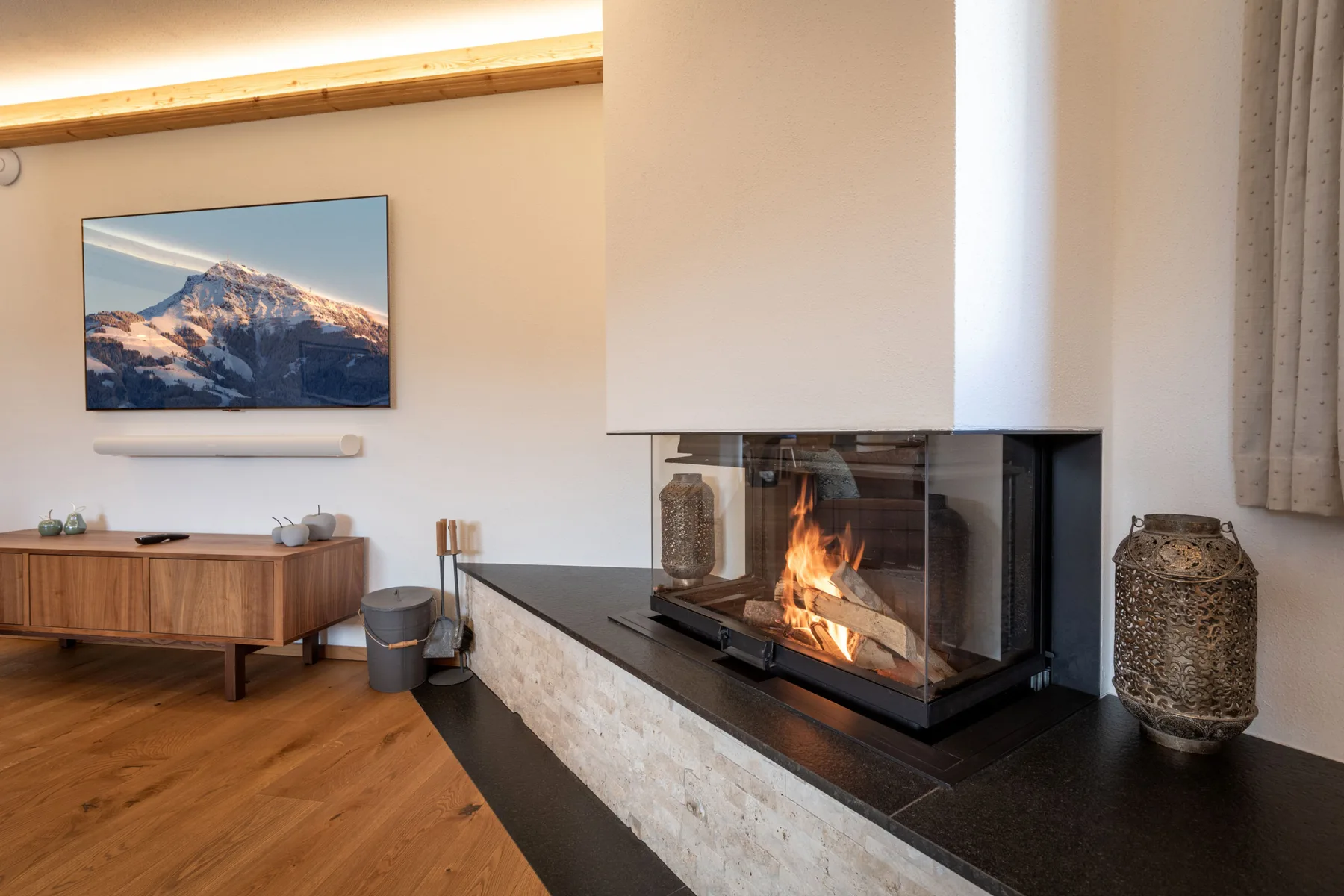 Una sala de estar con una chimenea de frente acristalado y un aparador de madera.