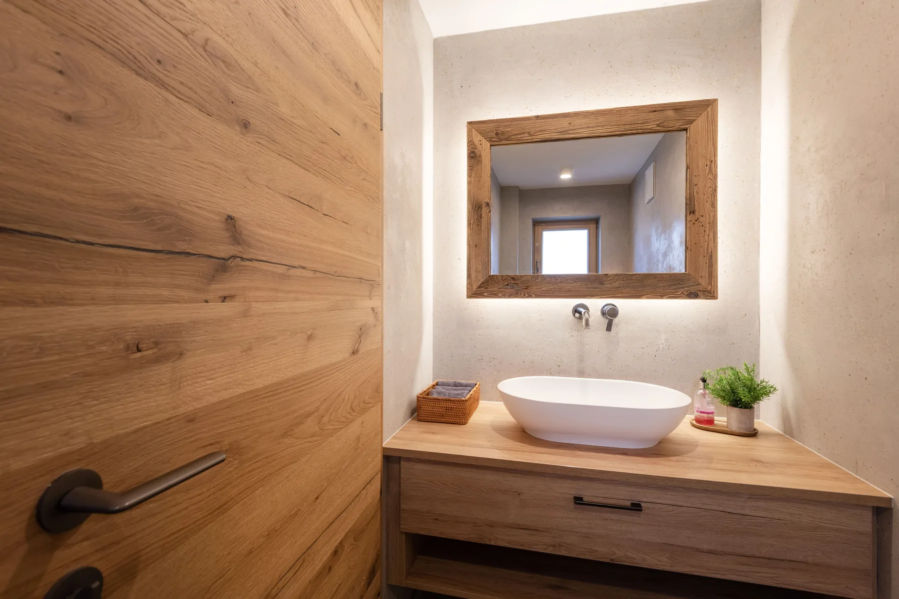 Un lavabo de baño con una pila sobrepuesta, grifería de pared y un espejo con marco de madera.