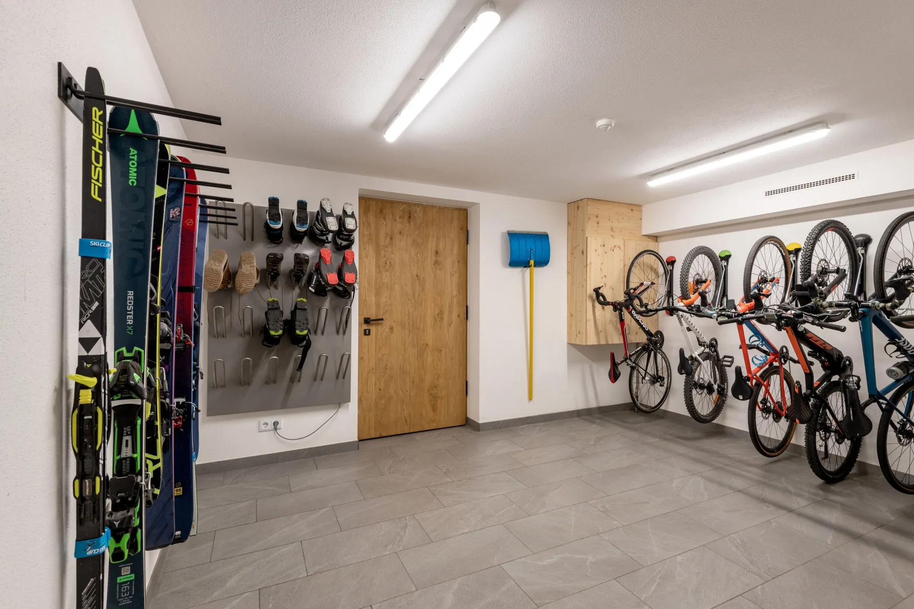 Zona común: Un cuarto para guardar bicicletas y esquís, con soportes y equipo en la pared.