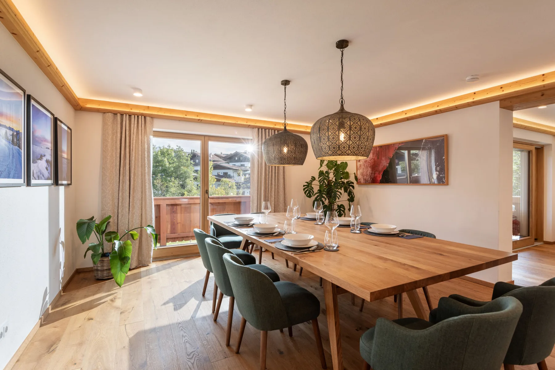 Un comedor con una mesa larga de madera, asientos tapizados y lámparas colgantes.
