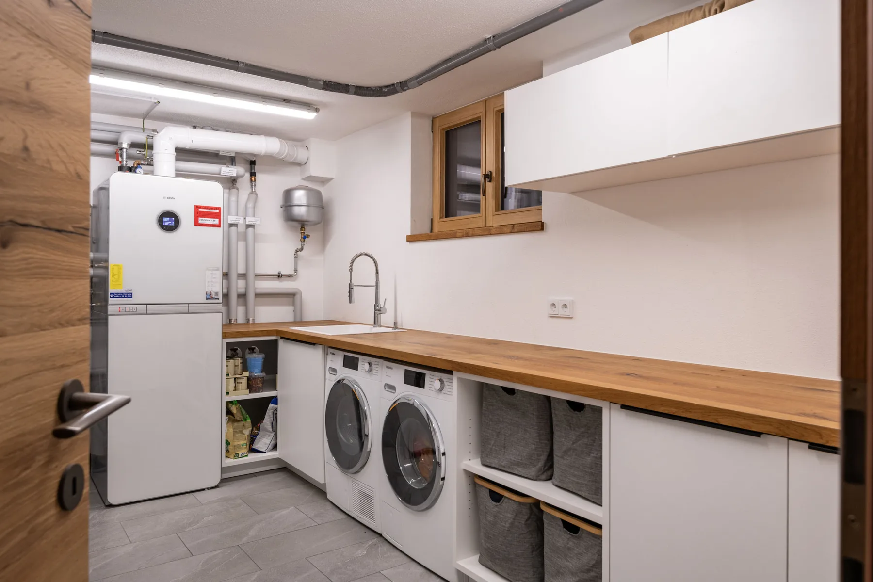 Zona común: Cuarto de lavandería con máquinas de lavado bajo una encimera de madera.