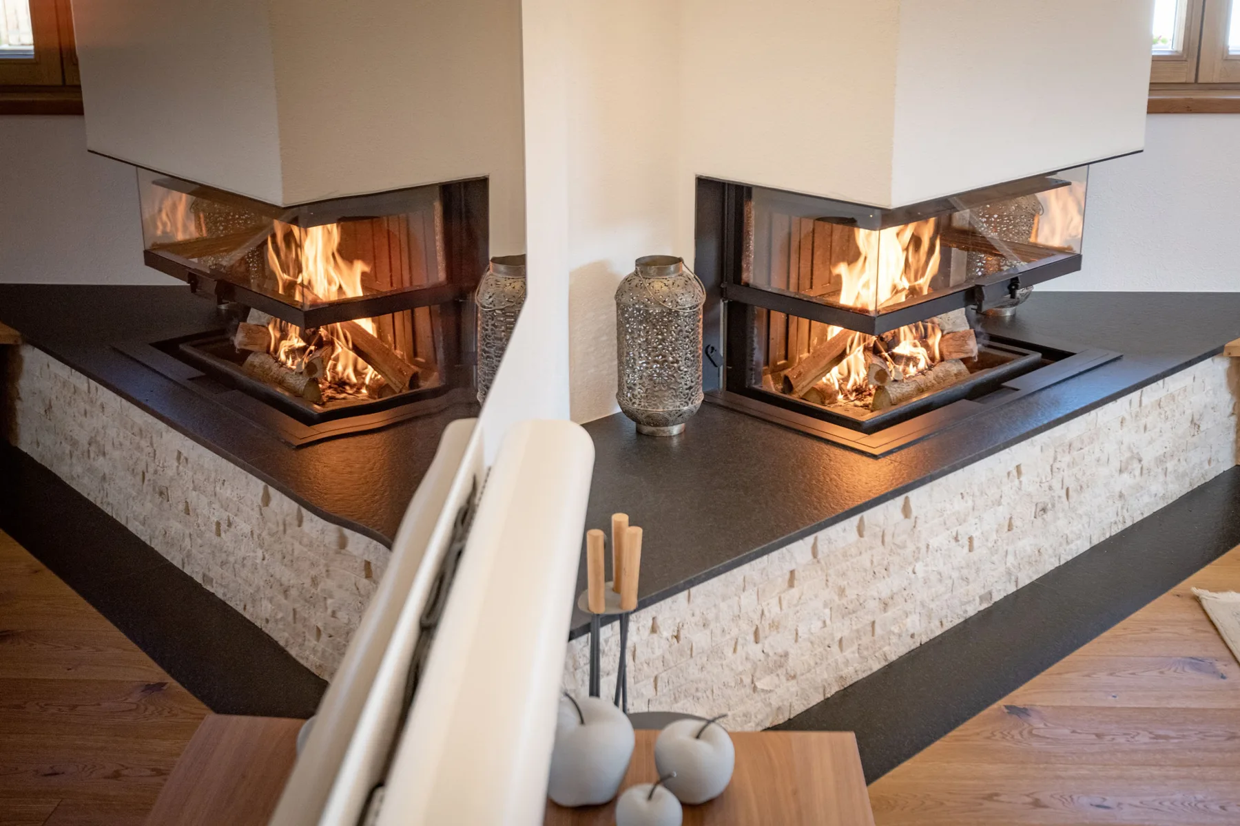 Una sala de estar cuenta con una chimenea de doble cara sobre una base revestida de piedra.