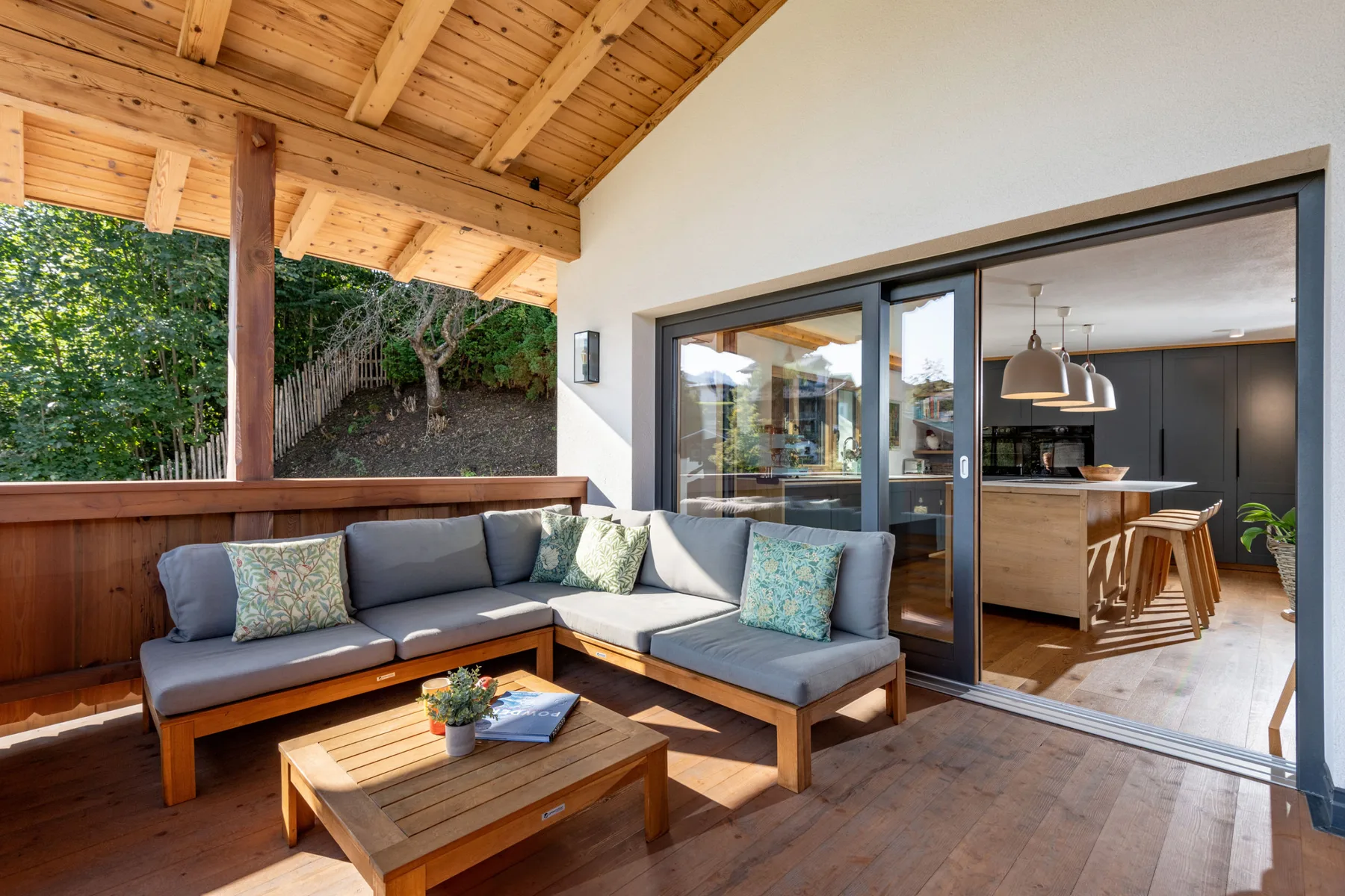 Una zona exterior cubierta con asientos se abre a una cocina moderna.