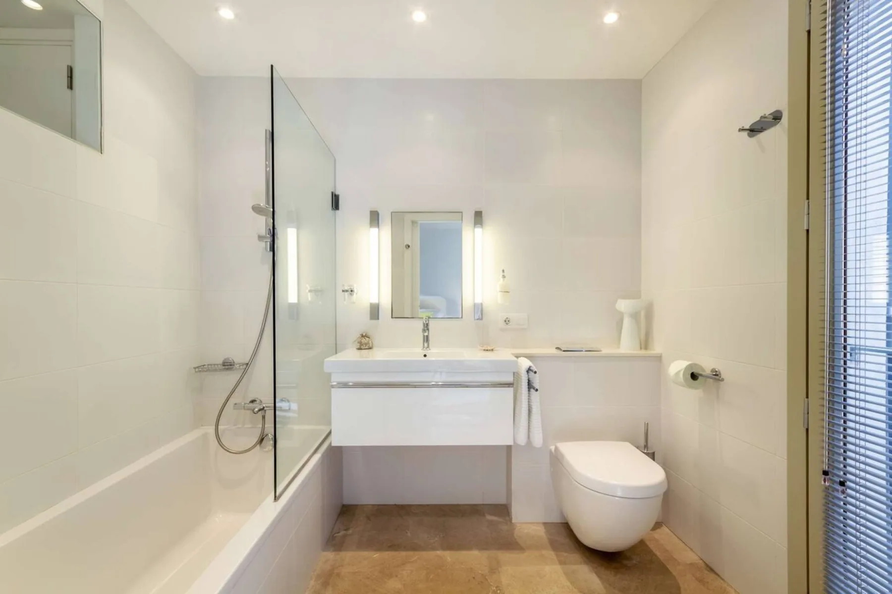 Un baño luminoso con bañera, lavabo e inodoro.