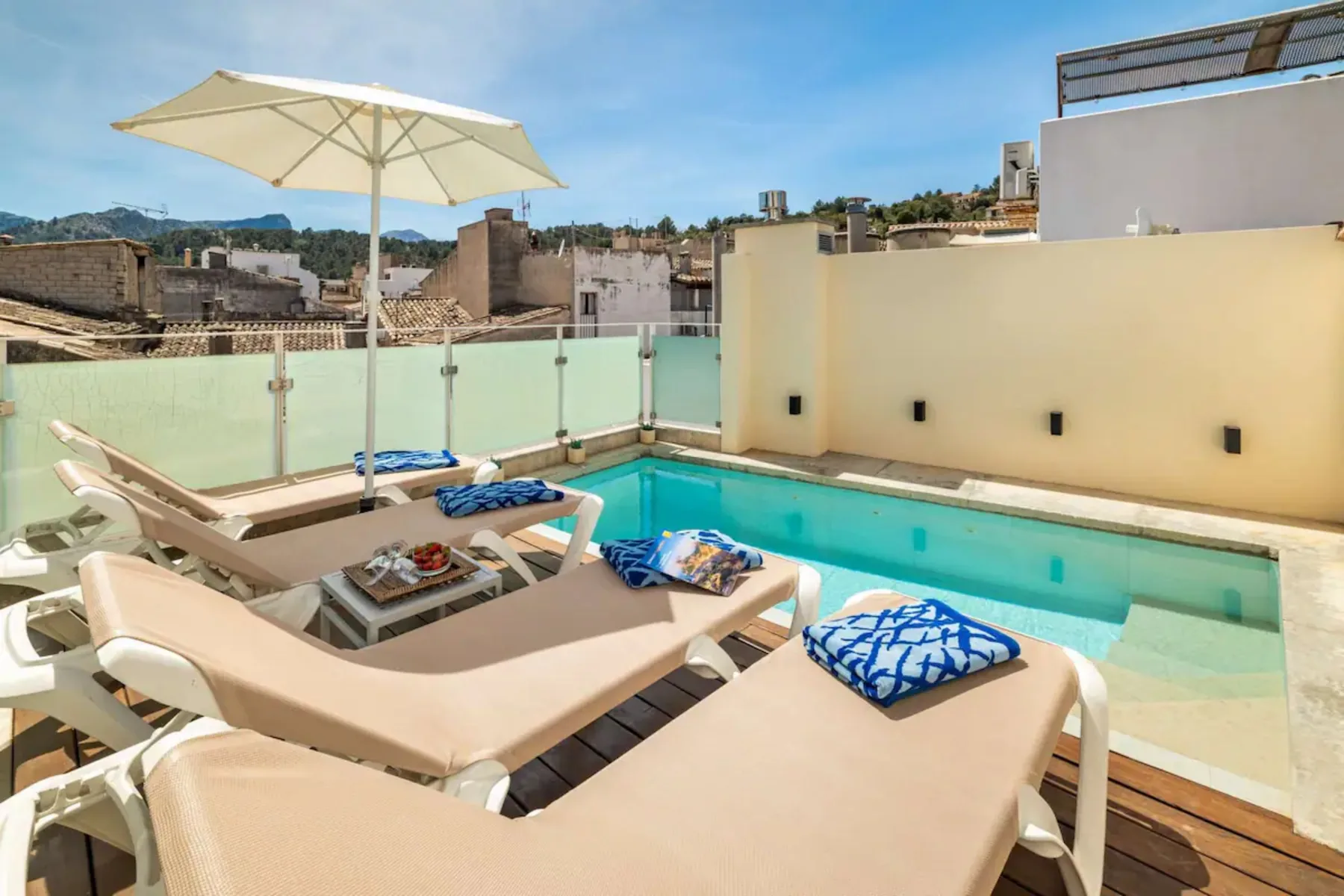 Una terraza con piscina en la azotea, tumbonas y una gran sombrilla.