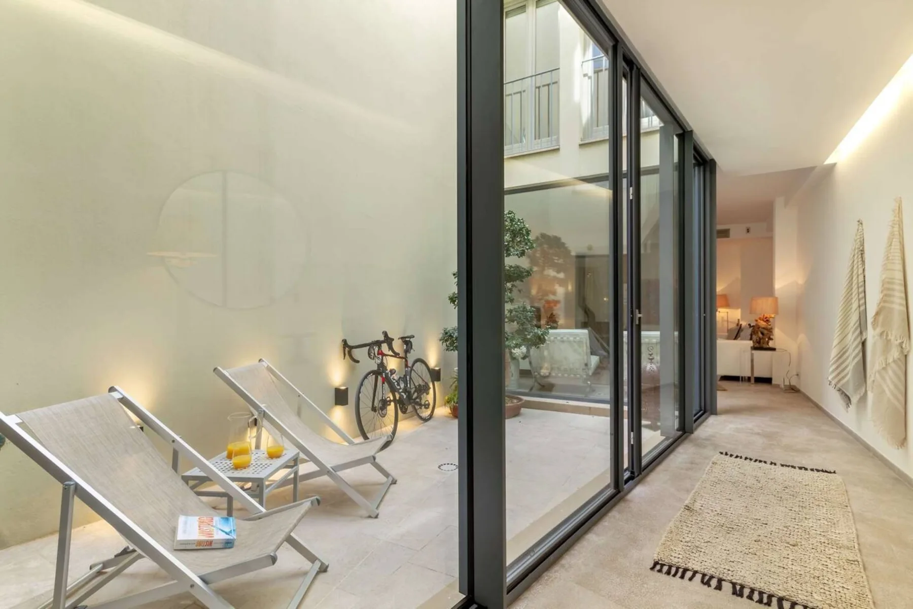 Un patio interior luminoso con asientos junto a puertas de vidrio de piso a techo.