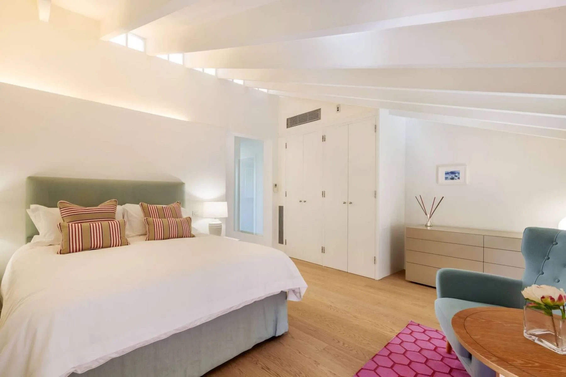 Un dormitorio luminoso con una cama grande y un sillón azul.