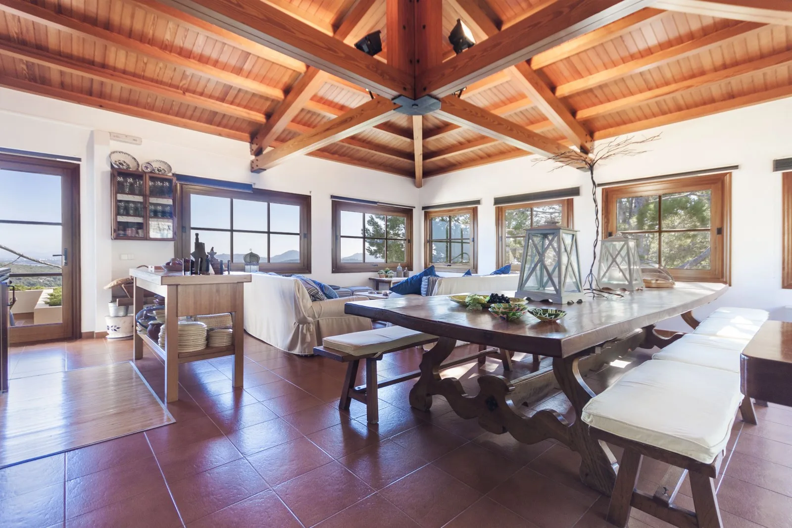 A bright dining area with a long wooden table beneath a vaulted timber ceiling.