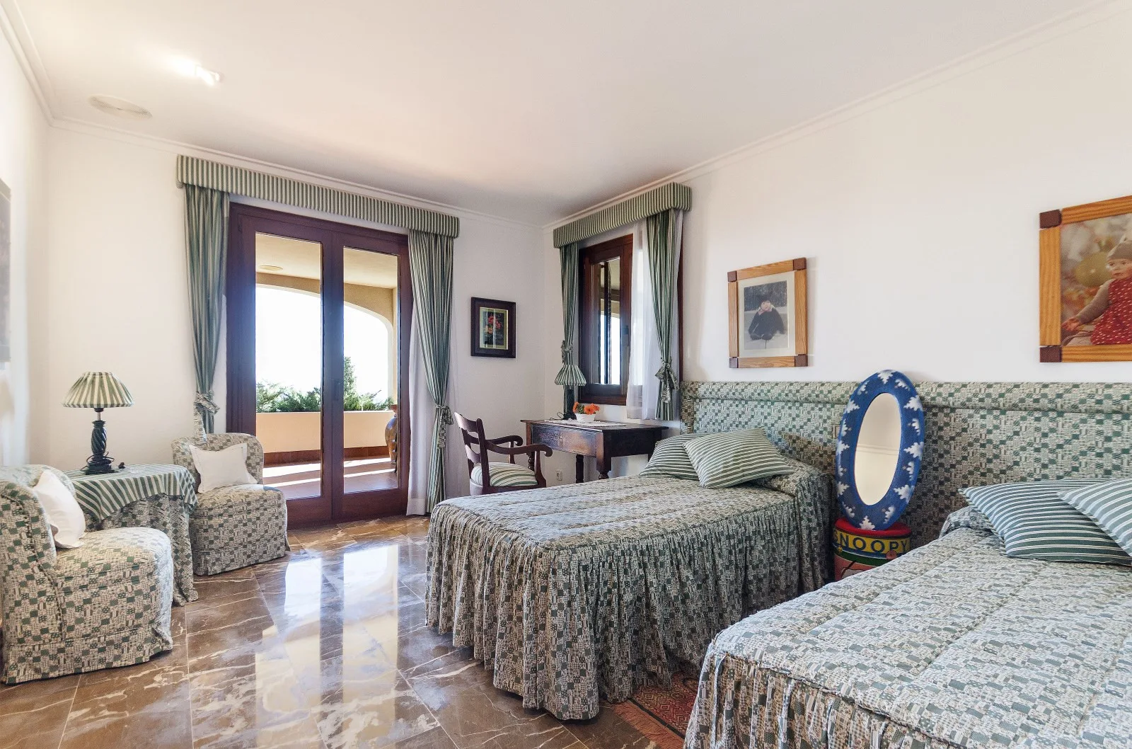 A bedroom with two beds, patterned bedding, and curtained windows.