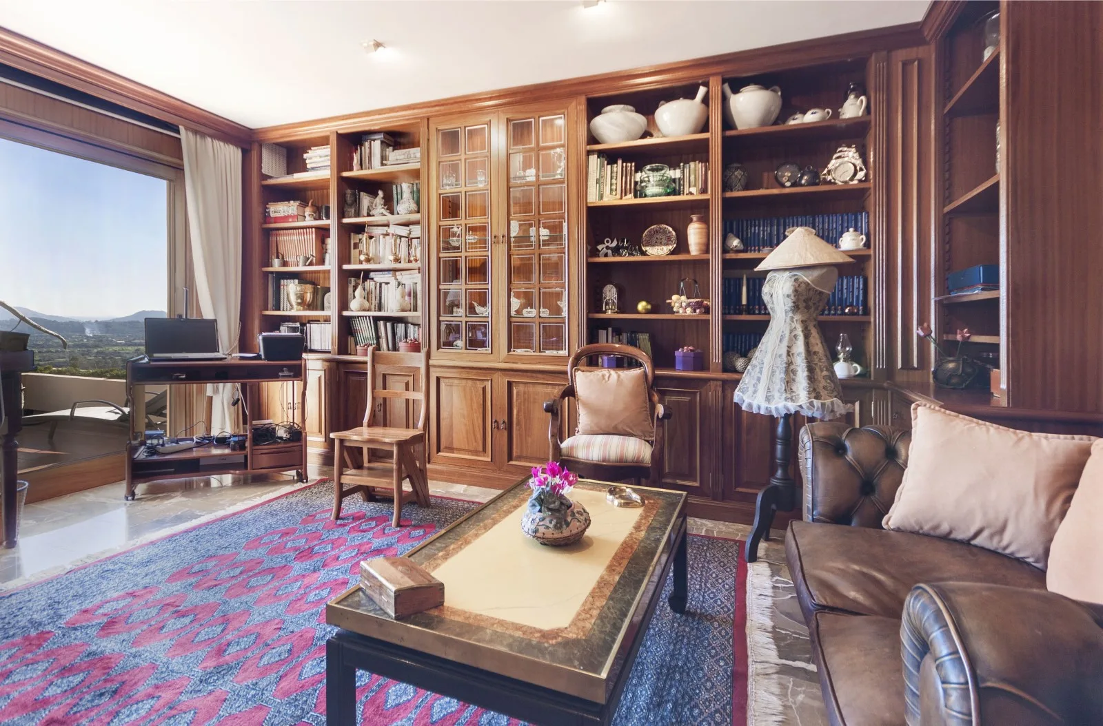 A living room with built-in wooden shelves, seating, and a central coffee table.