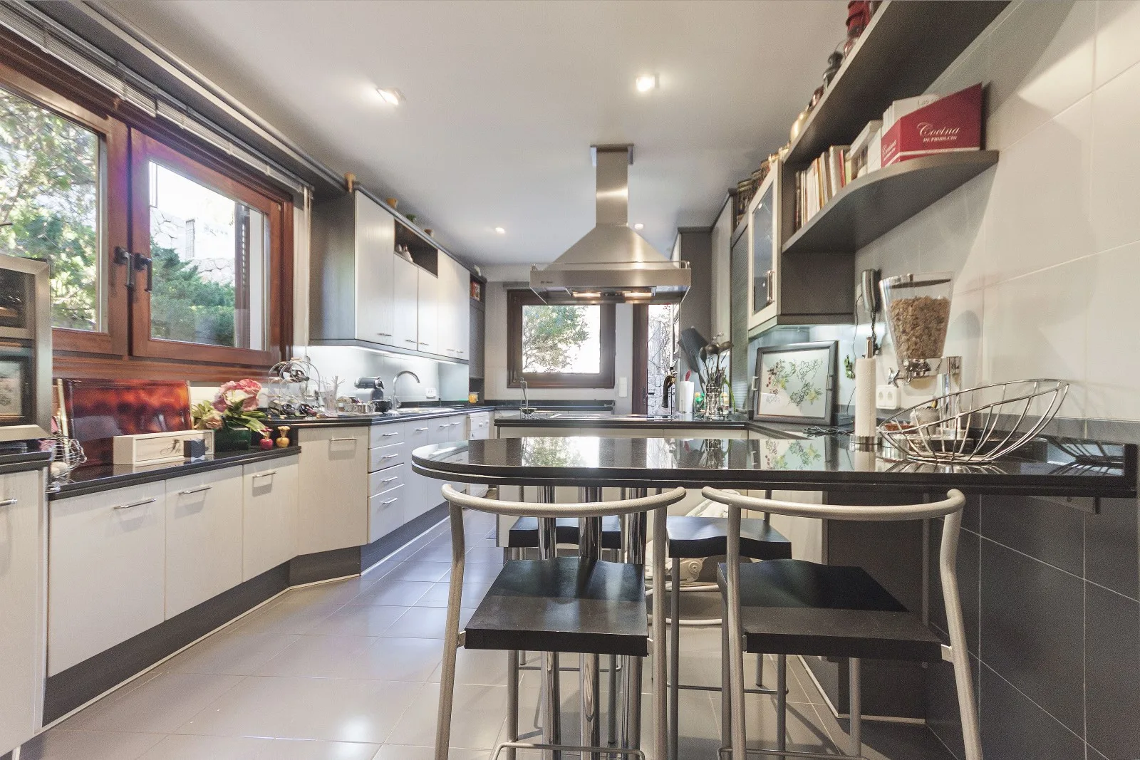A modern kitchen with a central island, bar seating, and large windows.