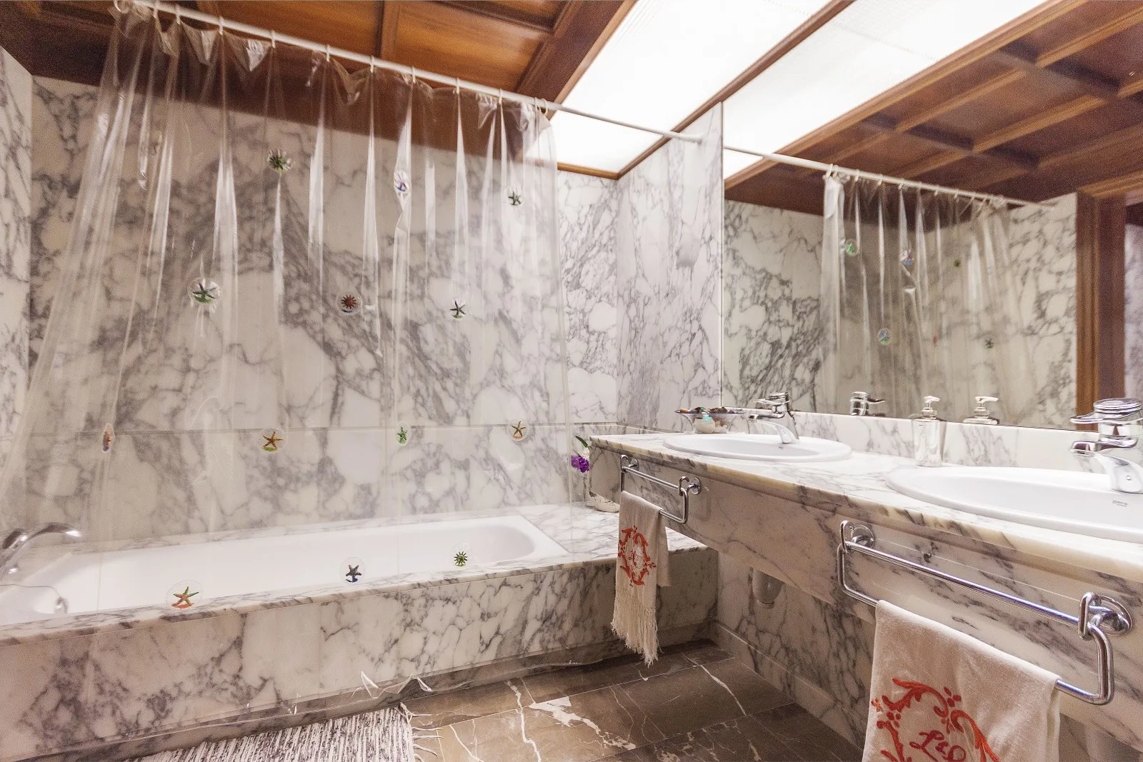 A marble bathroom with a bathtub, shower curtains, and a long sink counter.