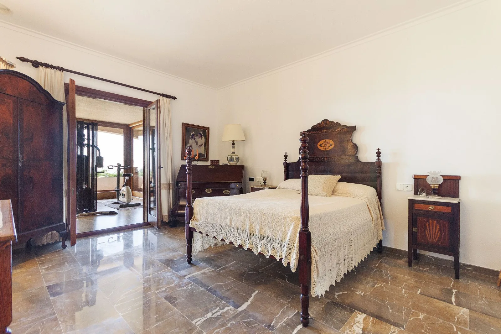 A bedroom with a large bed and dark wood furniture.