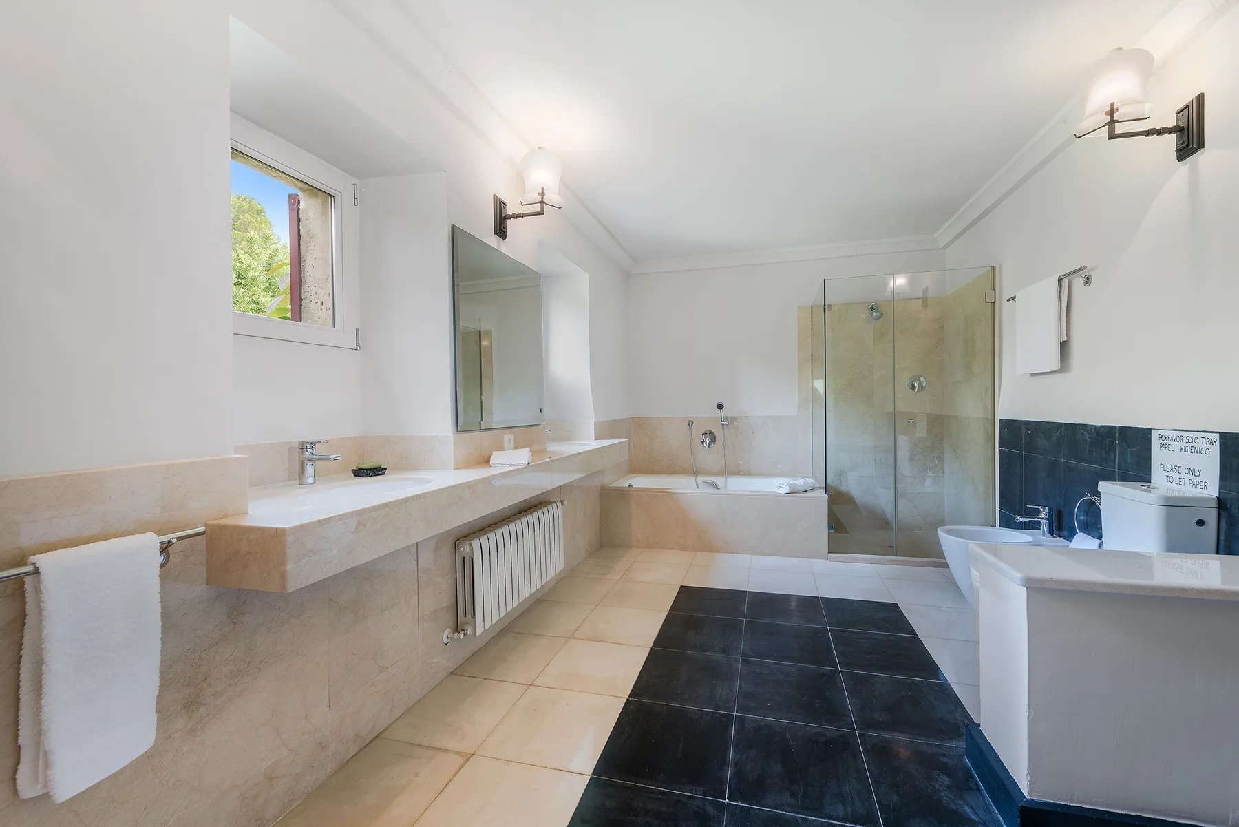 A bright bathroom with a long vanity, bathtub, and glass shower.