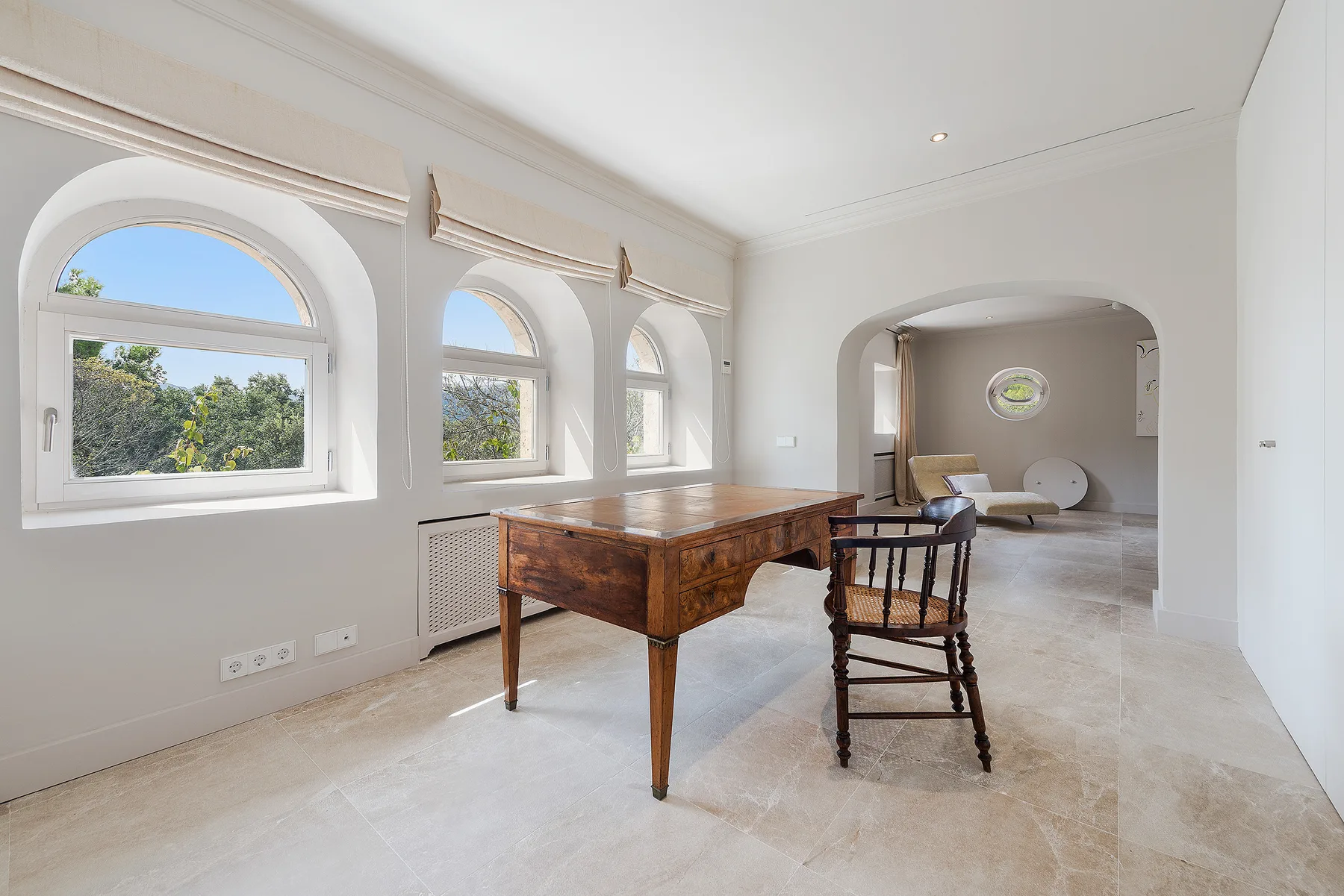 A bright interior room with arched windows and a wooden table.