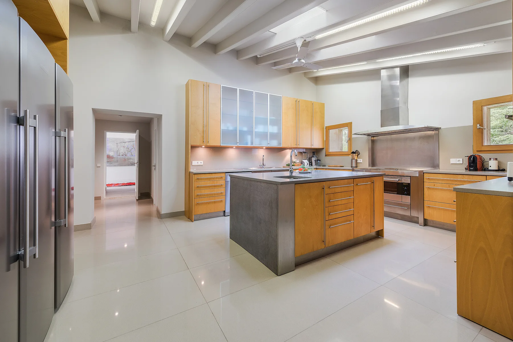 A spacious kitchen with a central island, wooden cabinetry, and stainless steel appliances.