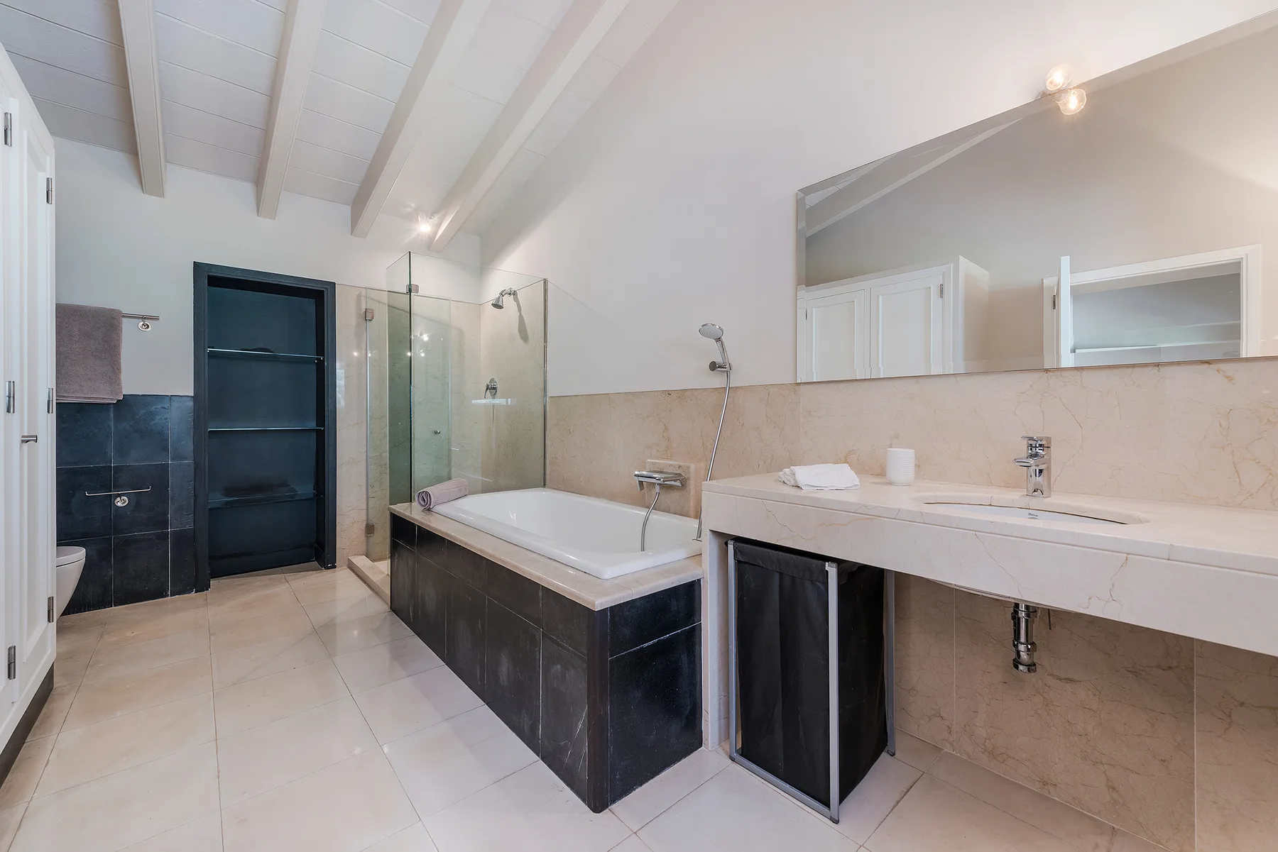 A spacious bathroom with a bathtub, glass shower area, and long vanity.