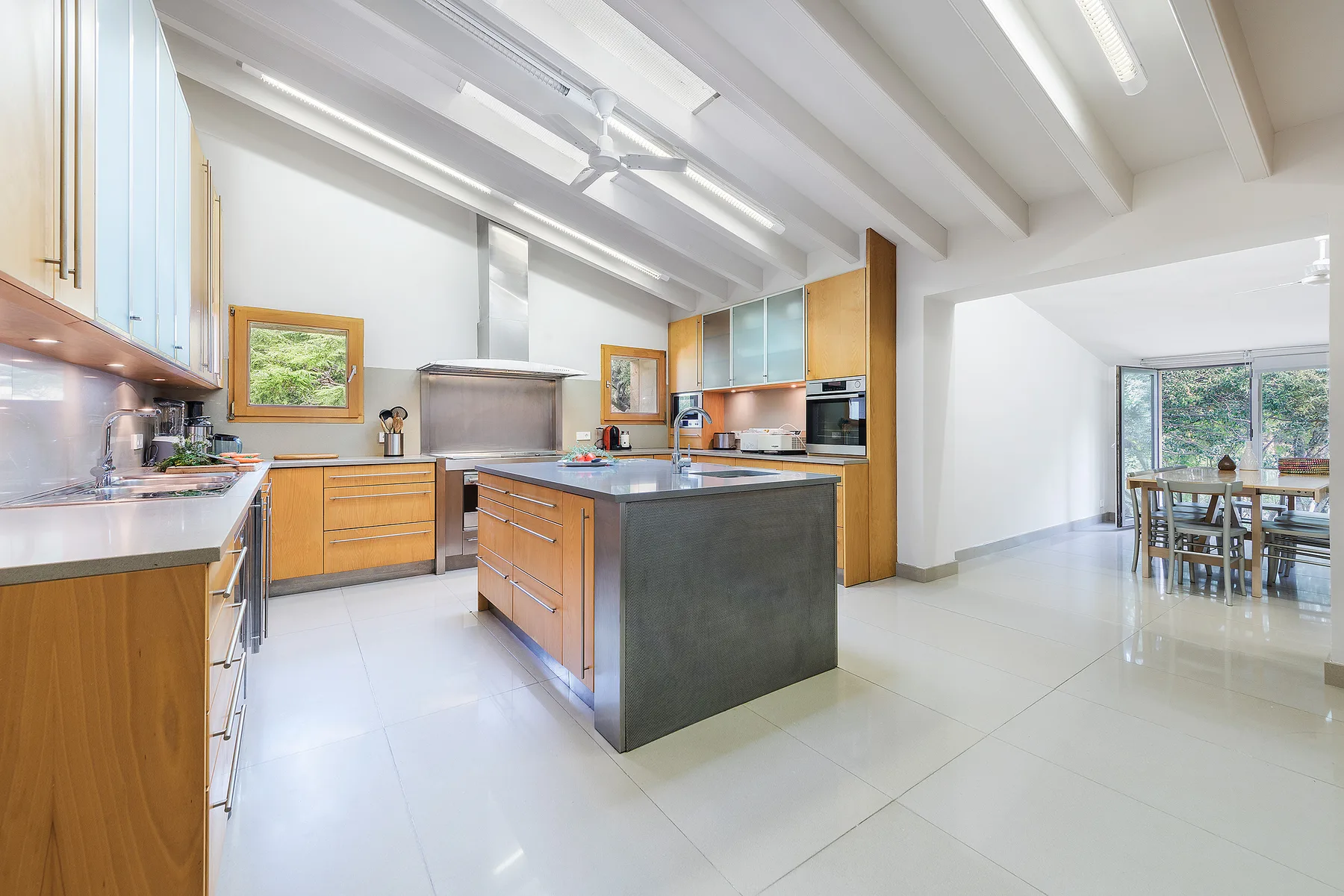 A bright kitchen with wooden cabinetry, a central island, and a dining area by the windows.