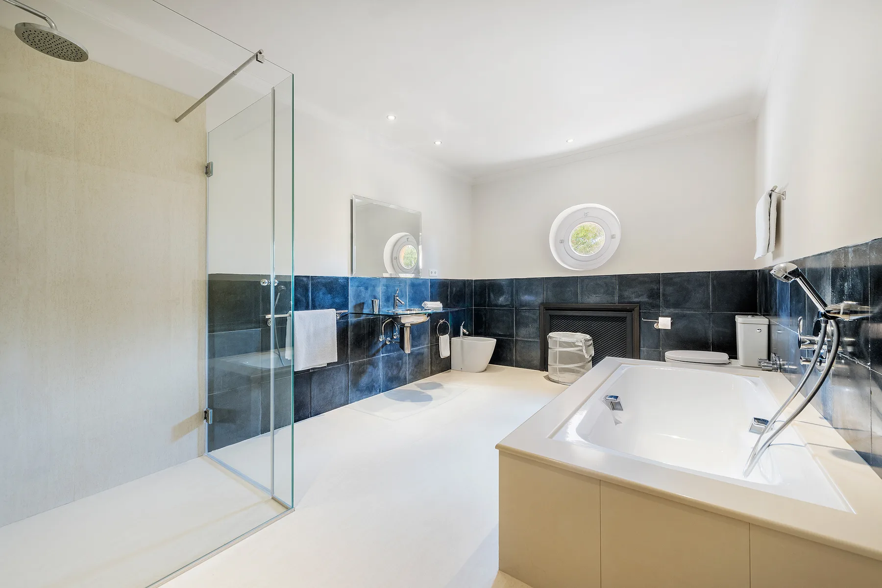 A bright bathroom with a glass shower and a large bathtub.