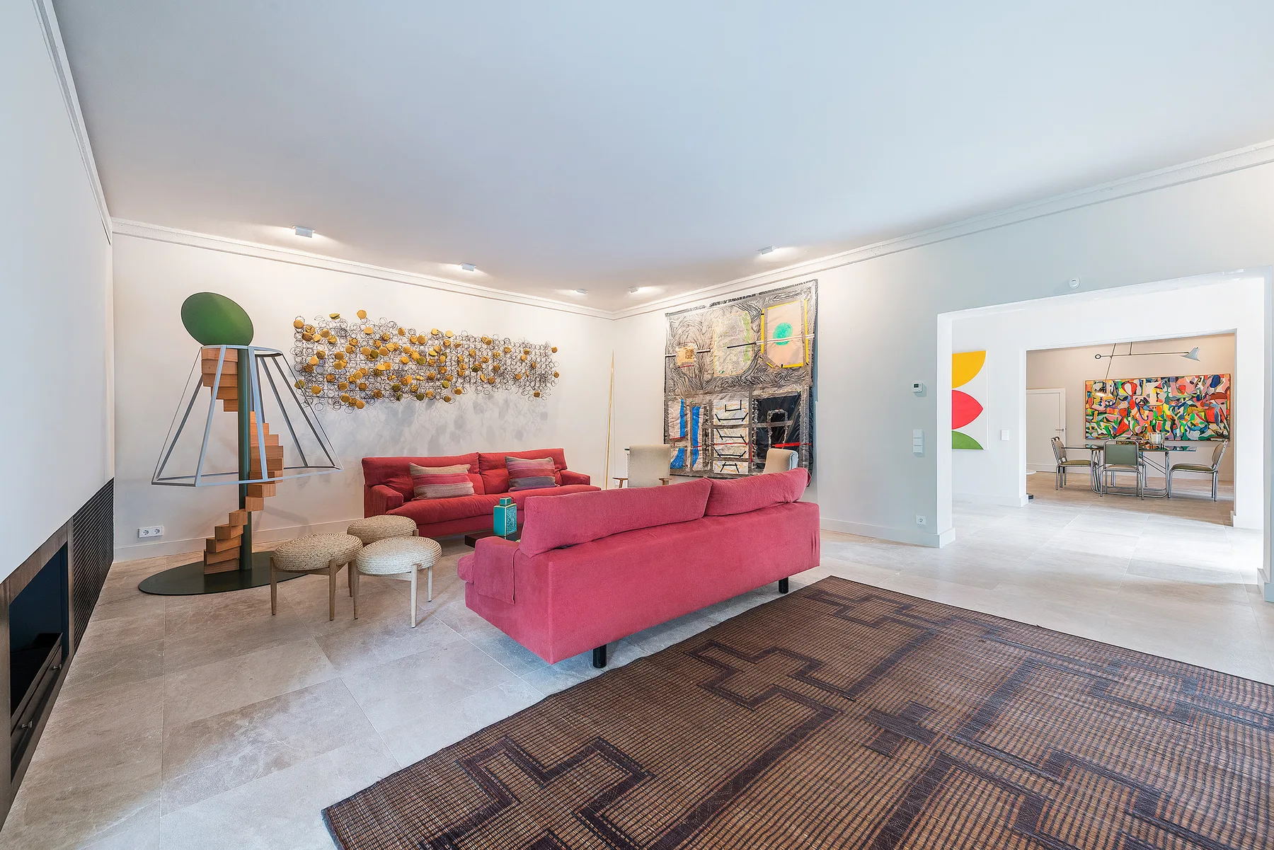 A living room with pink seating, a patterned rug, and colorful wall art.