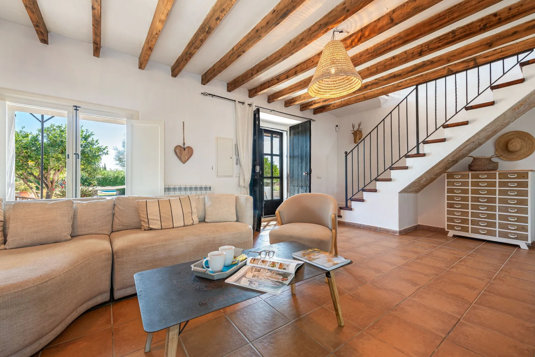 Una sala de estar luminosa con asientos, una mesa de centro y una escalera.