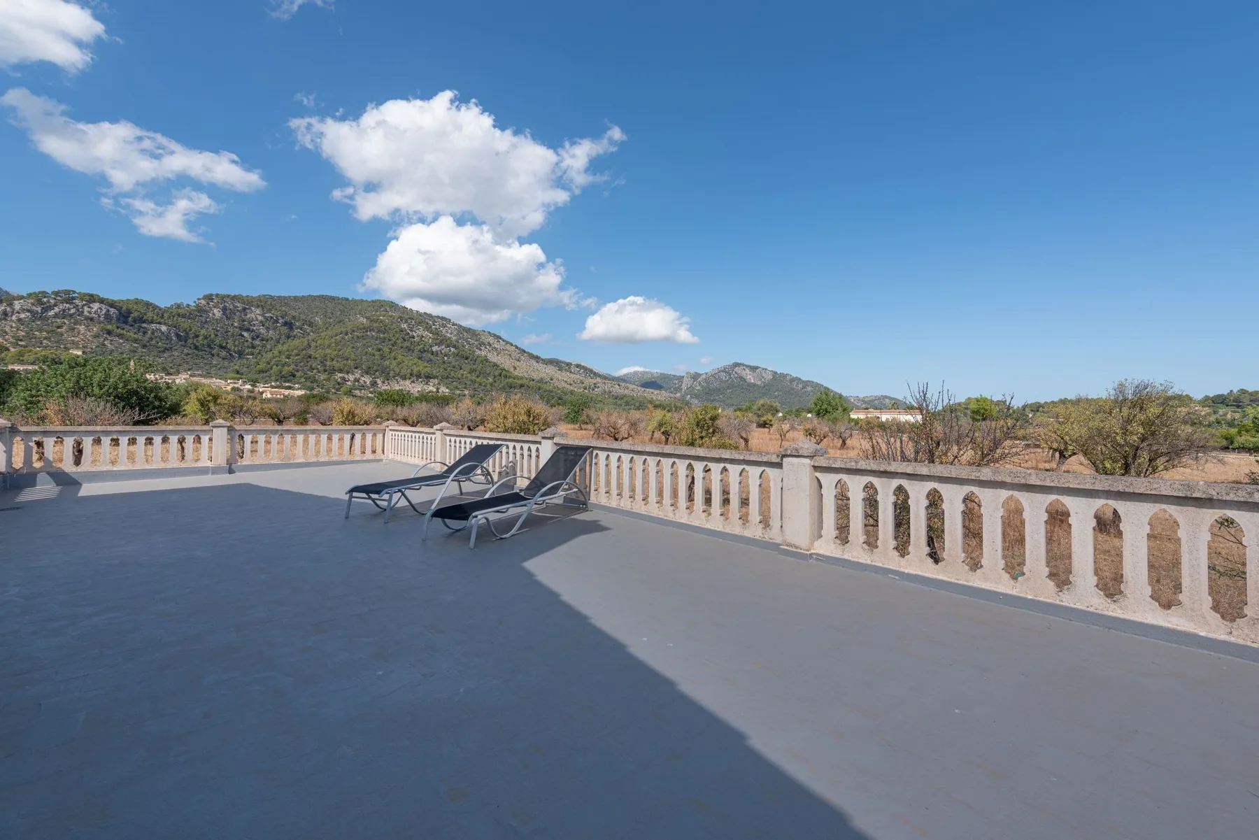 Una amplia terraza con asientos de descanso tiene vistas a un paisaje montañoso.