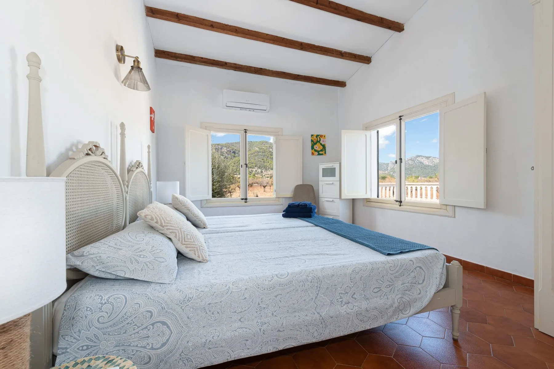 Un dormitorio luminoso con una cama grande y ventanas con vistas al paisaje.