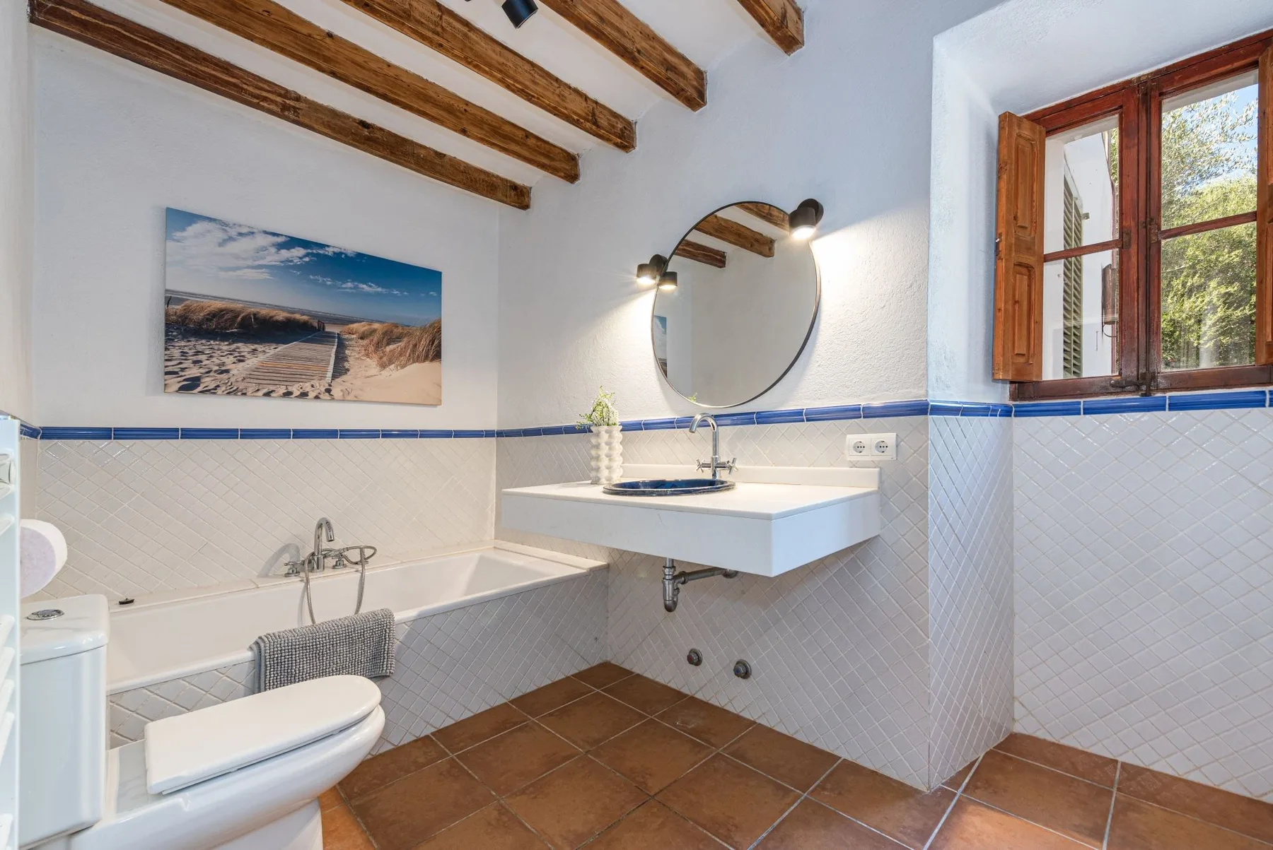 Un baño con bañera, inodoro y lavabo suspendido.