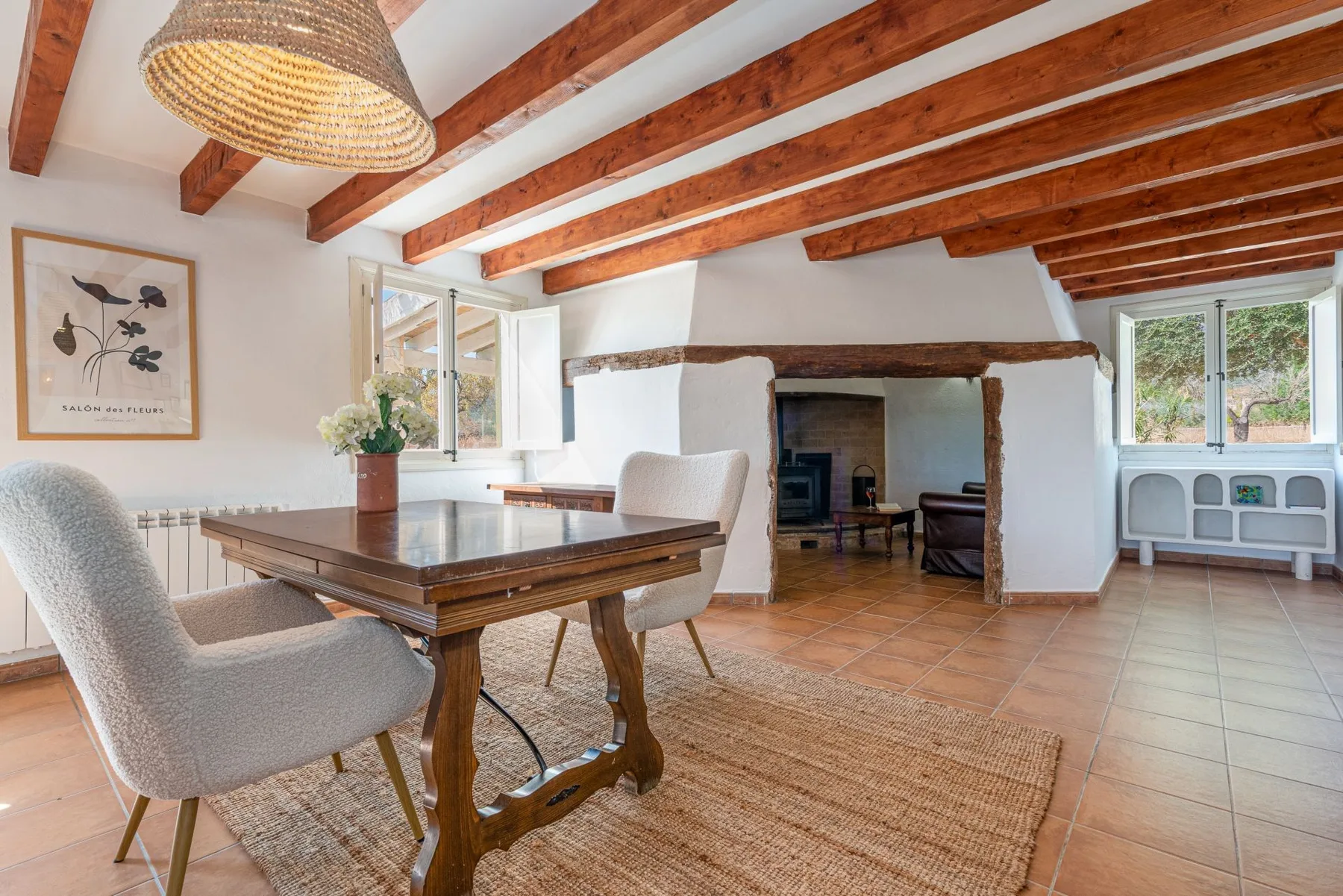 Comedor con una mesa de madera y sillas bajo vigas de techo expuestas.