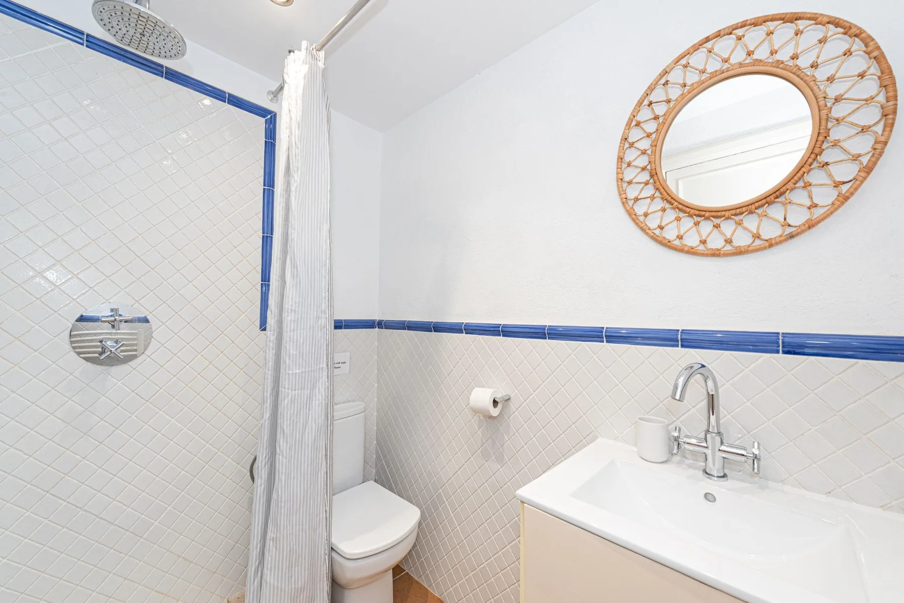 Un baño luminoso con ducha, inodoro y lavabo.